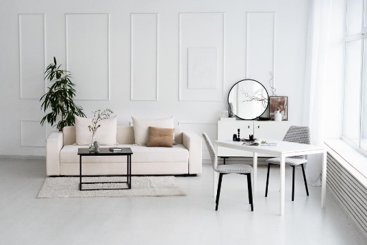 белые диван и столик в комнате  с большим зеркалом