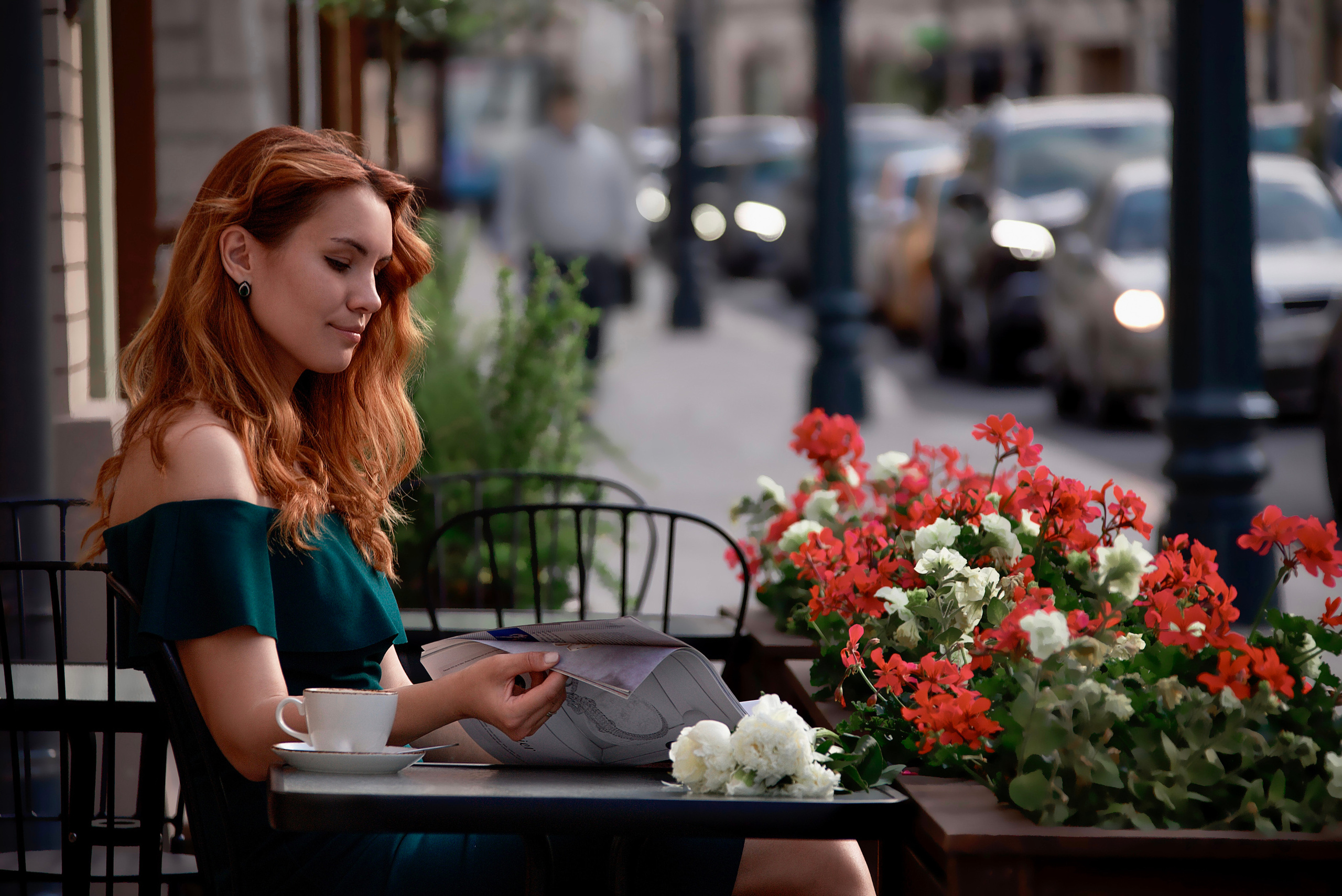 Фотосессия девушки в кафе за столиком она смотрит журнал в весенний день.