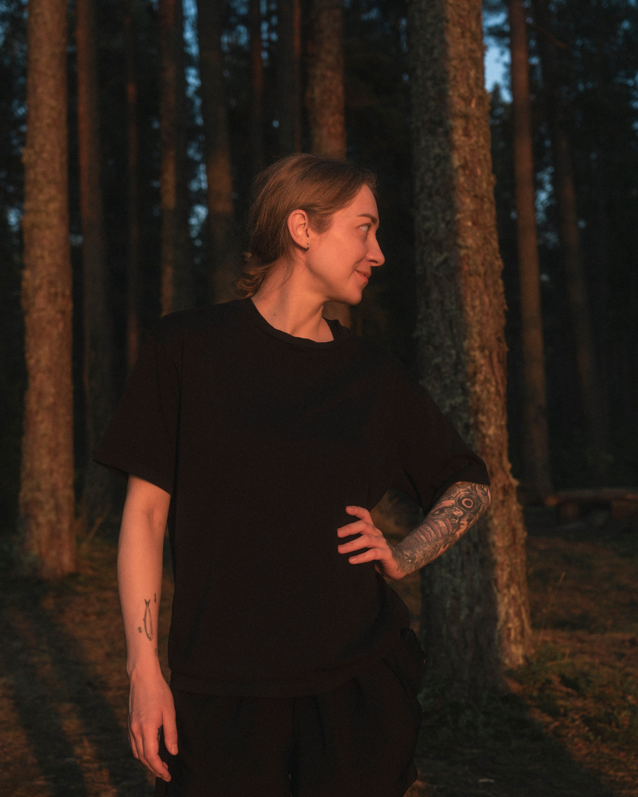 Фотография девушки одетой в черное на закате в лесу Ленинградской области.