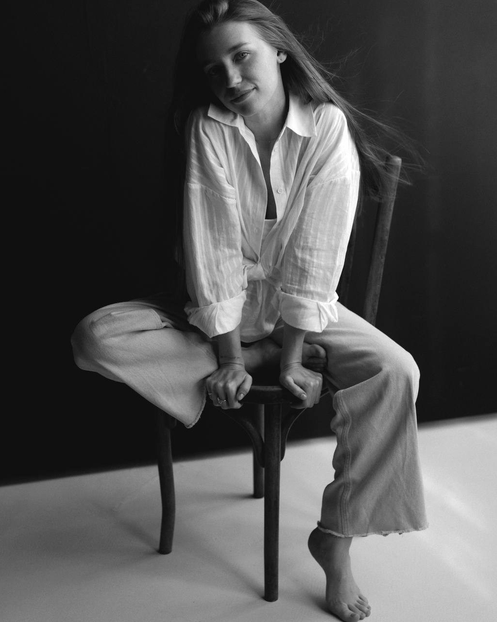 Чёрно-белый портрет: модель сидит на стуле в рубашке