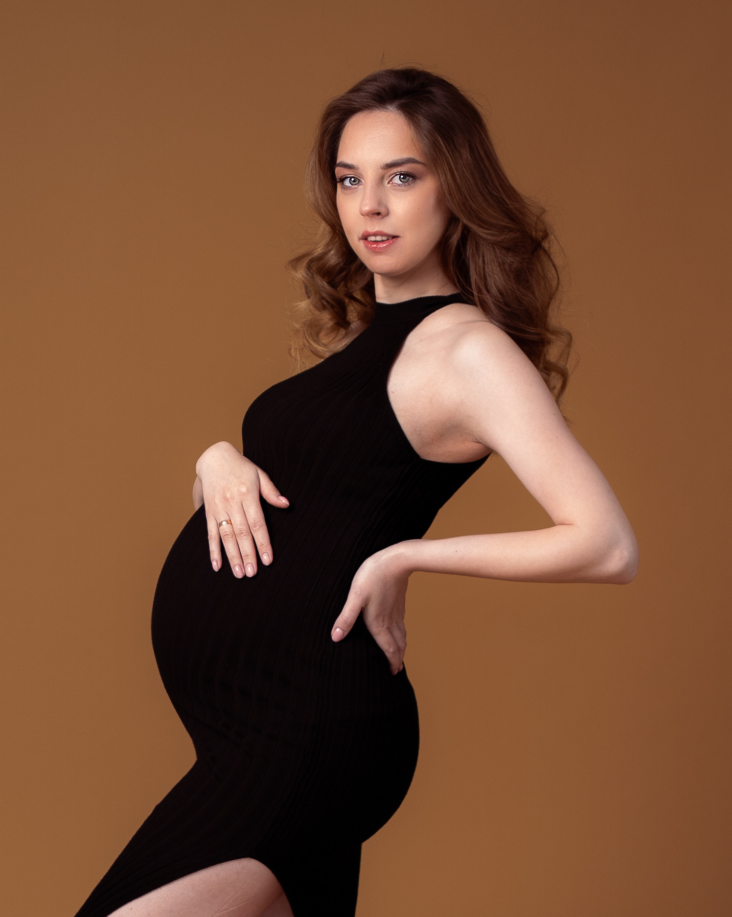 беременная девушка позирует в студии в красивом платье