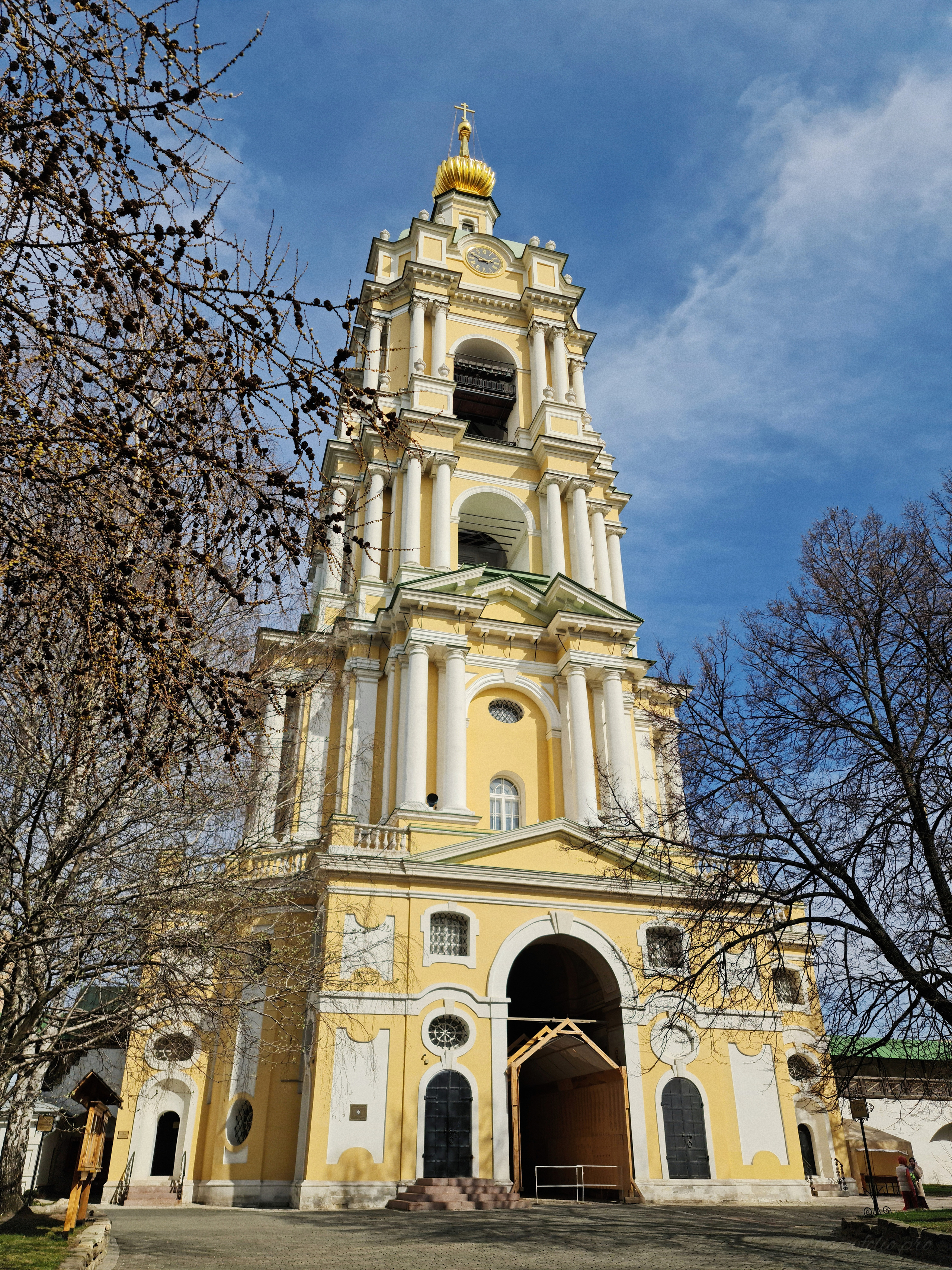Фотография колокольни колокольня с храмом преподобного Сергия Радонежского (XVIII век) в ясный солнечный день весной.