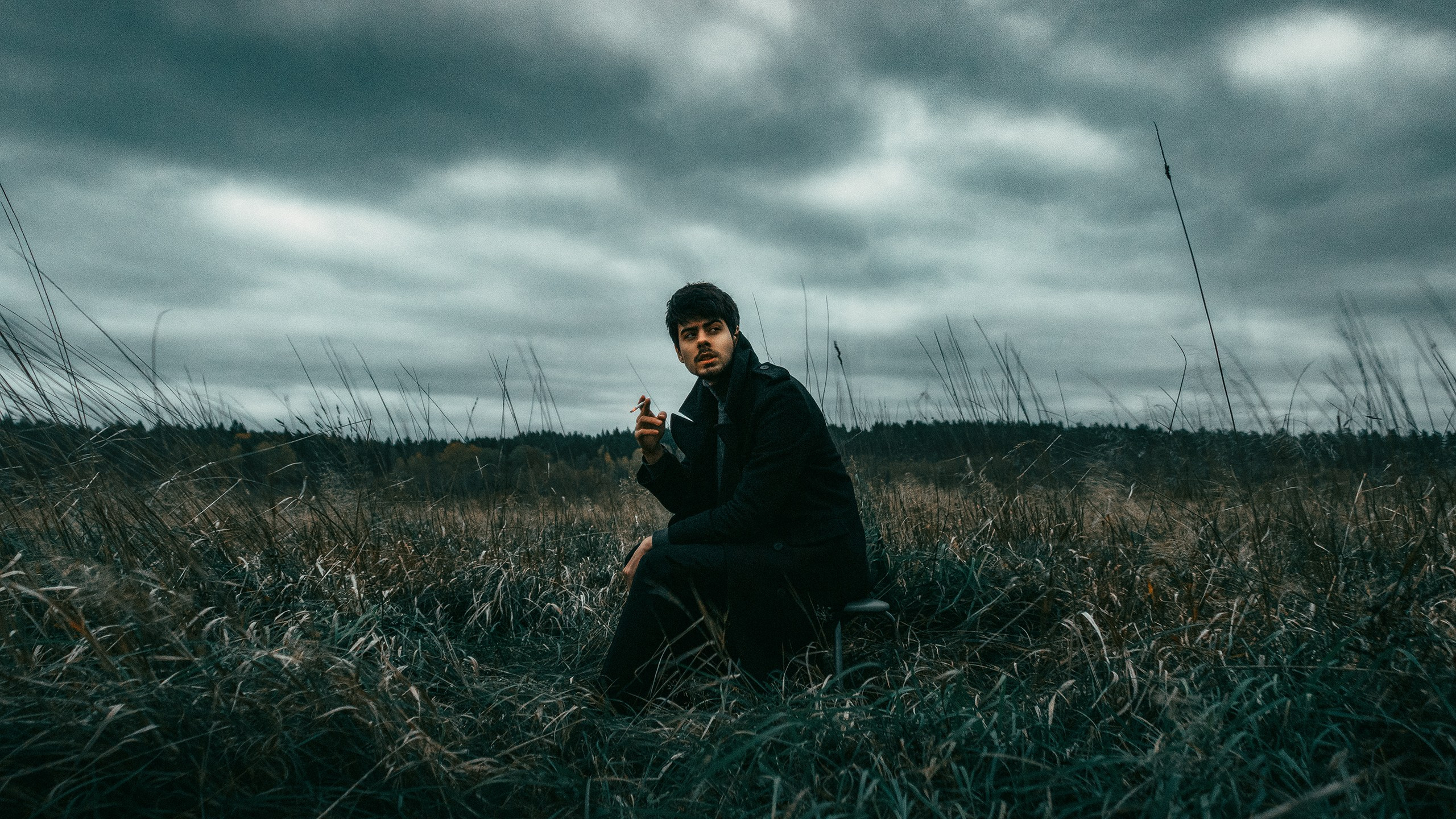 Девушка в светлой одежде сидит на деревянном стуле на поляне у соснового леса, атмосферный портрет на природе при жёстком солнечном дневном свете