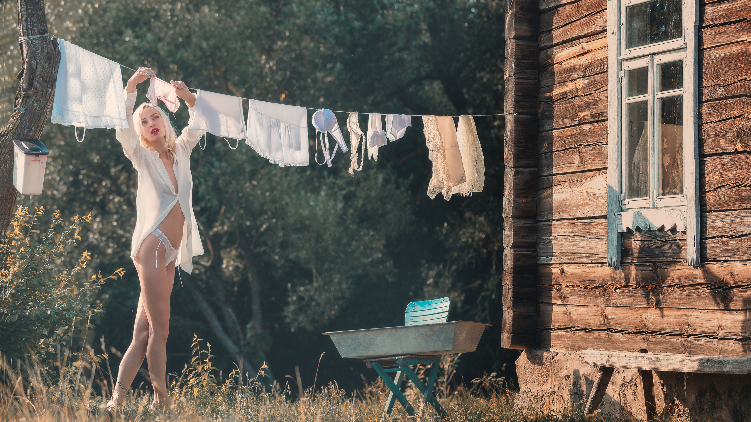 блондинка в рубашке и трусиках развешивает белье
