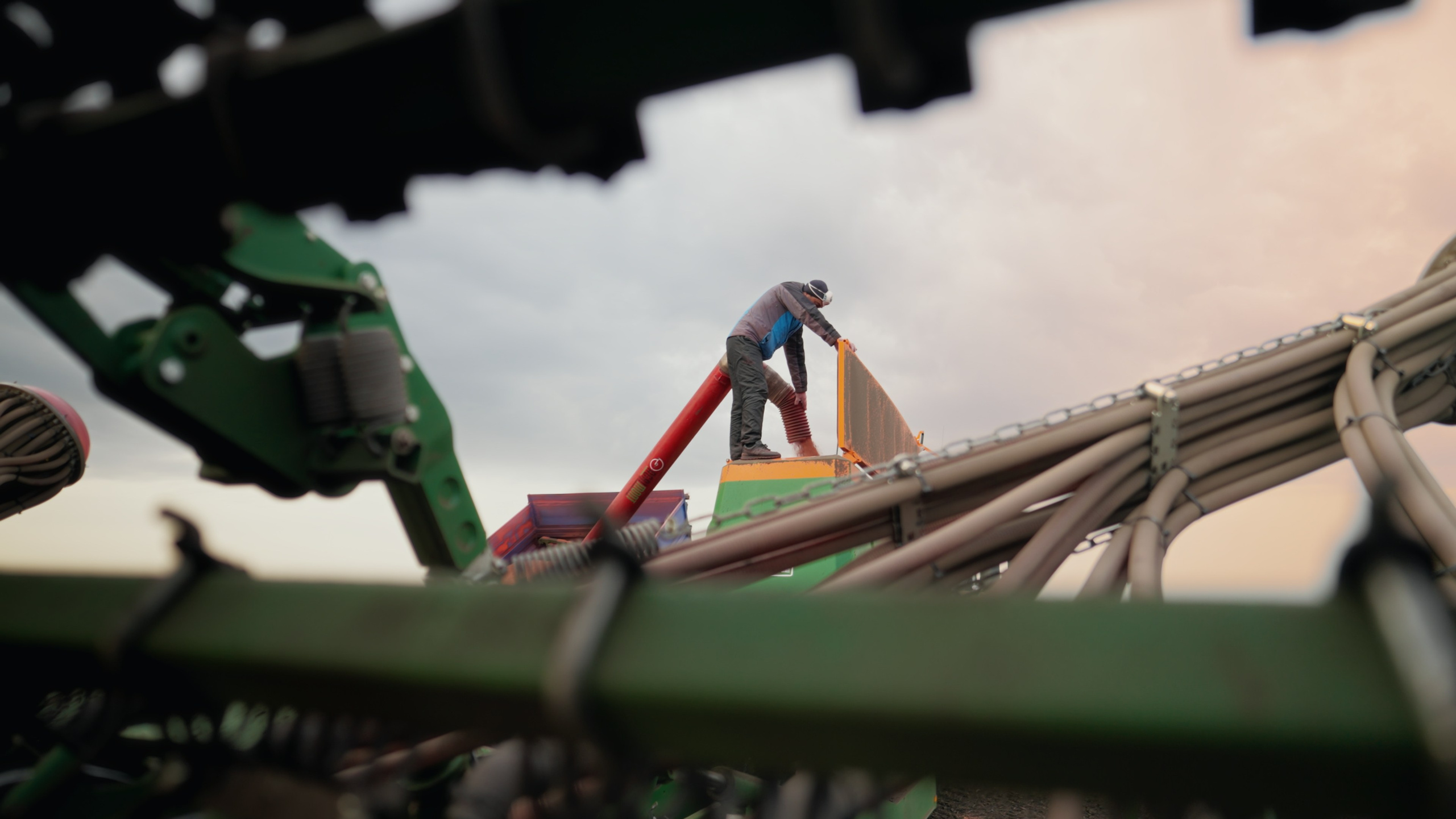 Комбайнер заполняет комбайн во время посевной профессиональная съемка для аграриев