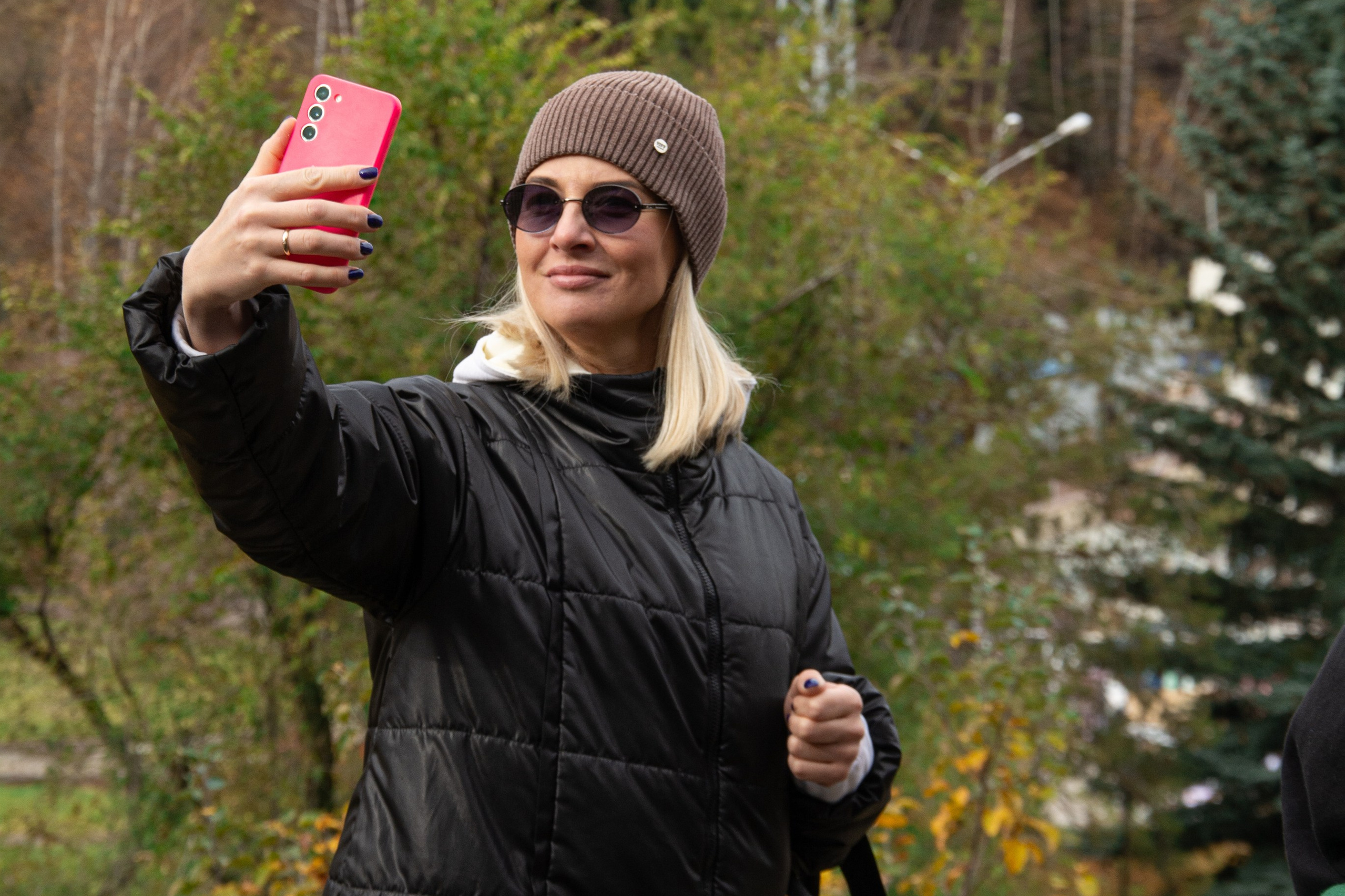 Величественный Чарынский каньон в районе Алматы с ярко-красными скалами, пересечённый извилистой дорогой, на которую падают длинные вечерние тени. Захватывающее сочетание красочных утёсов, зелёных склонов и драматичного неба создаёт эффектный пейзаж