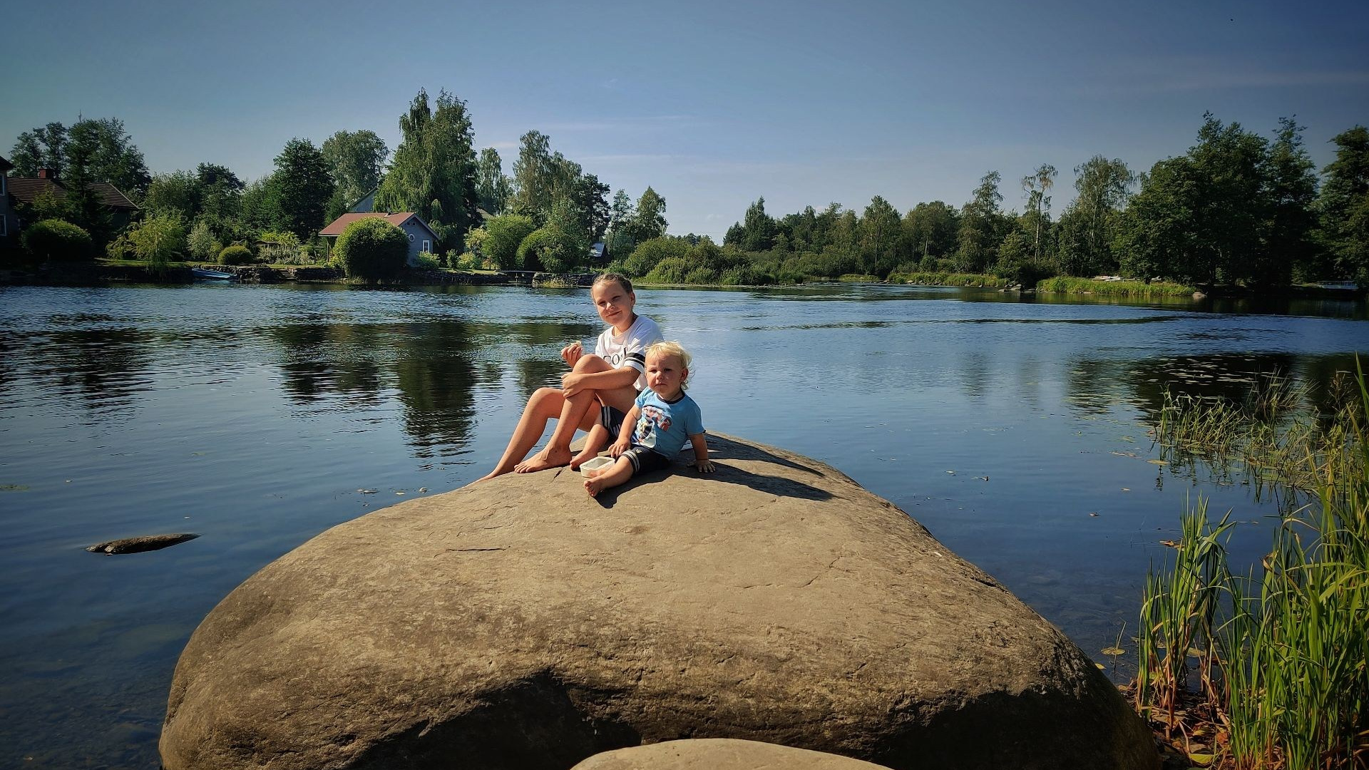 На камне у реки Вуокса сидят девочка и мальчик, наслаждаясь природой