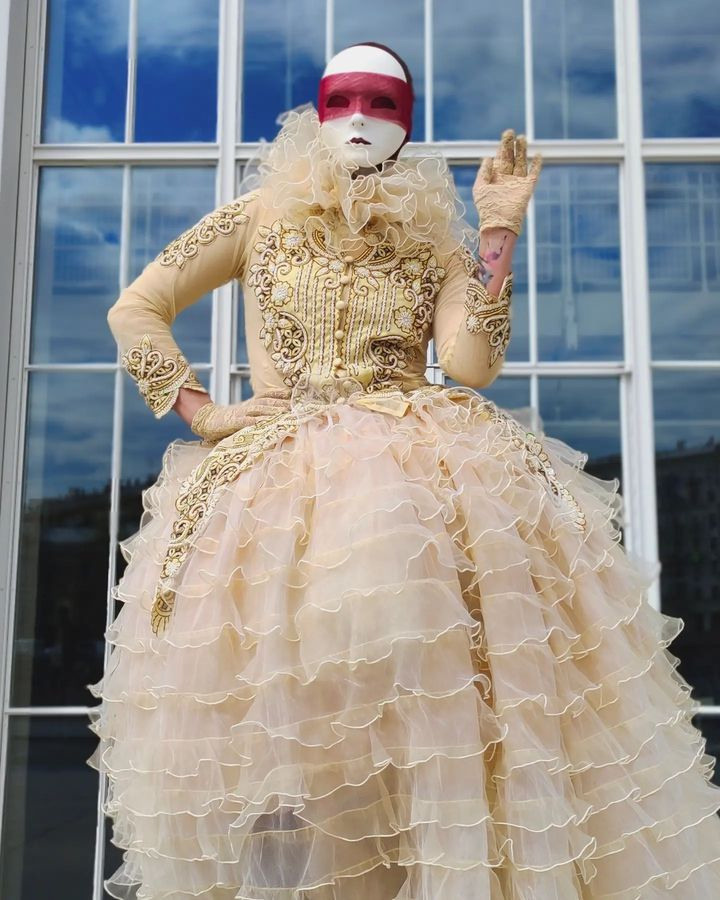 Ходулист машет рукой и позирует свадебному фотографу на празднике.