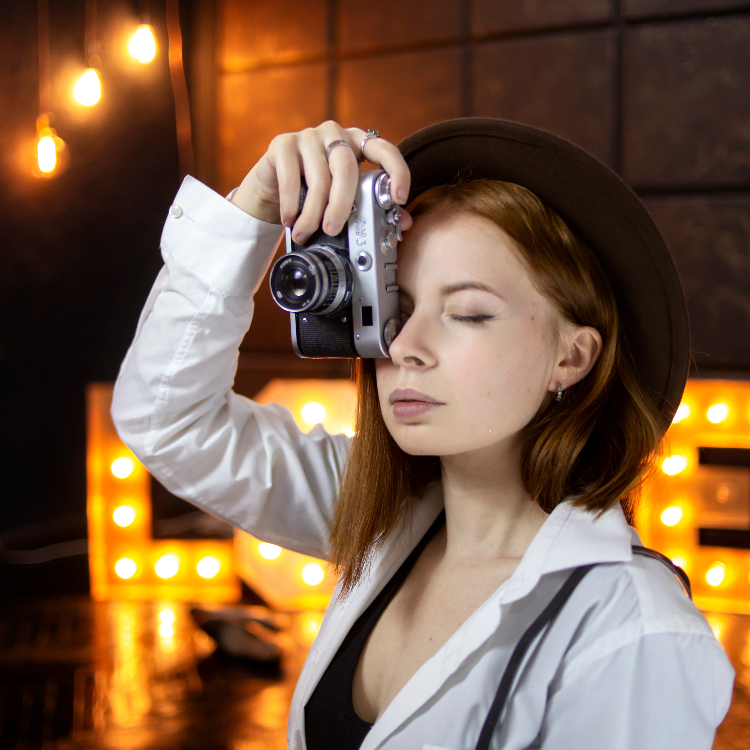 Девушка фотограф в шляпе держит фотокамеру