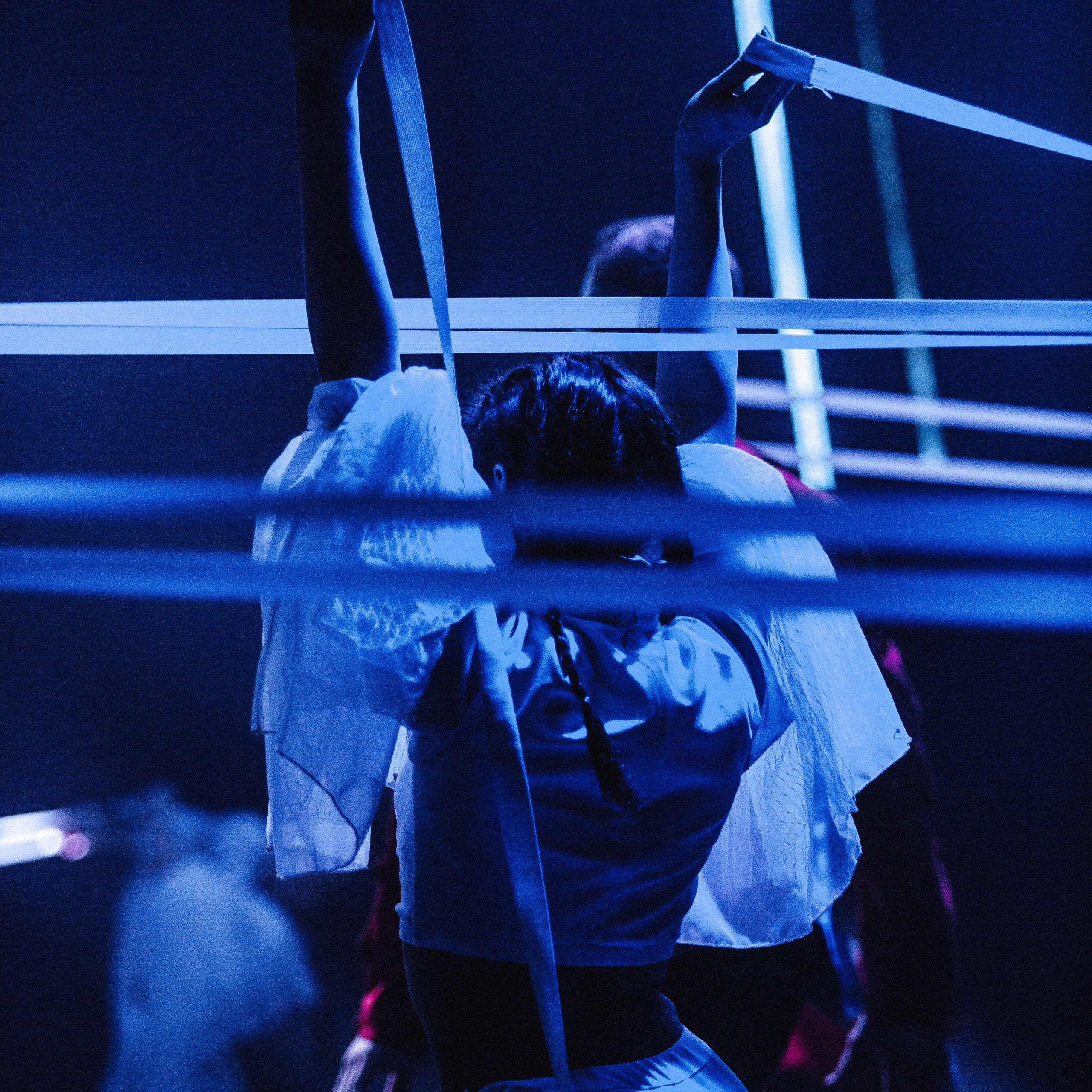 Артистка балета в сценическом освещении поднимает руки на фоне лент