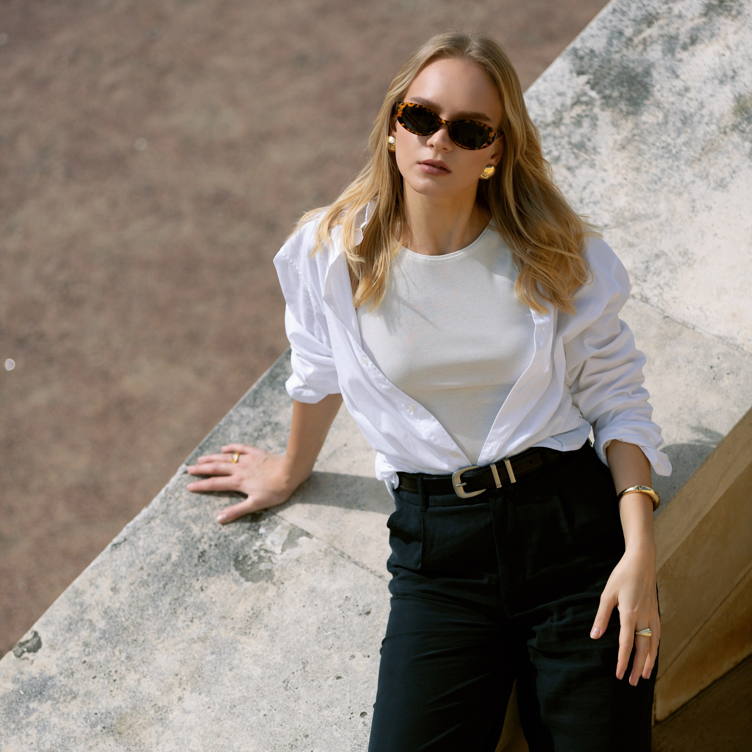 Девушка сидит на каменной лестнице в белой рубашке и чёрных штанах. Фототерапия и переосмысление себя через образы.