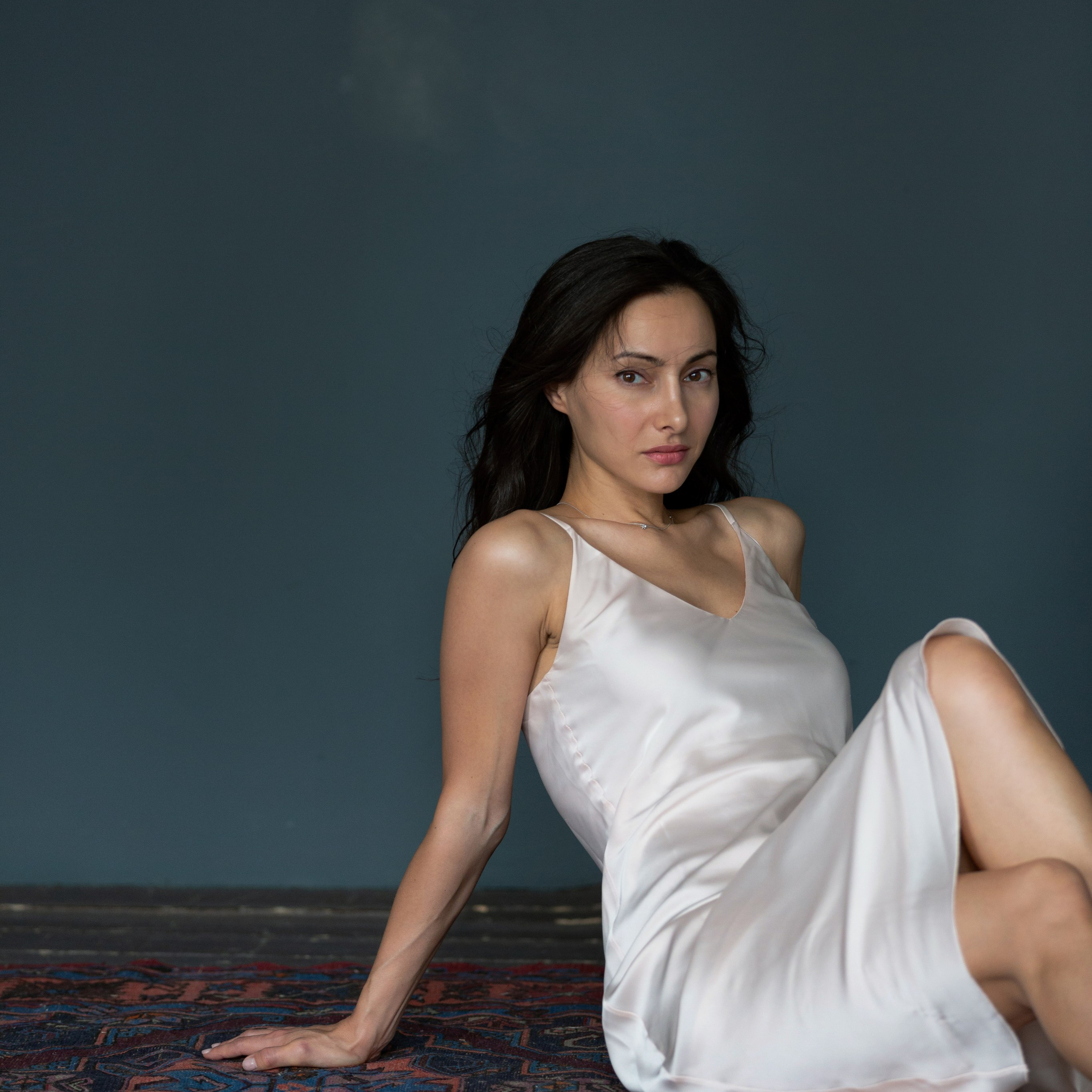 Девушка сидит на ковре в студии в уютной атмосфере. Тёплая фотосессия как подарок.