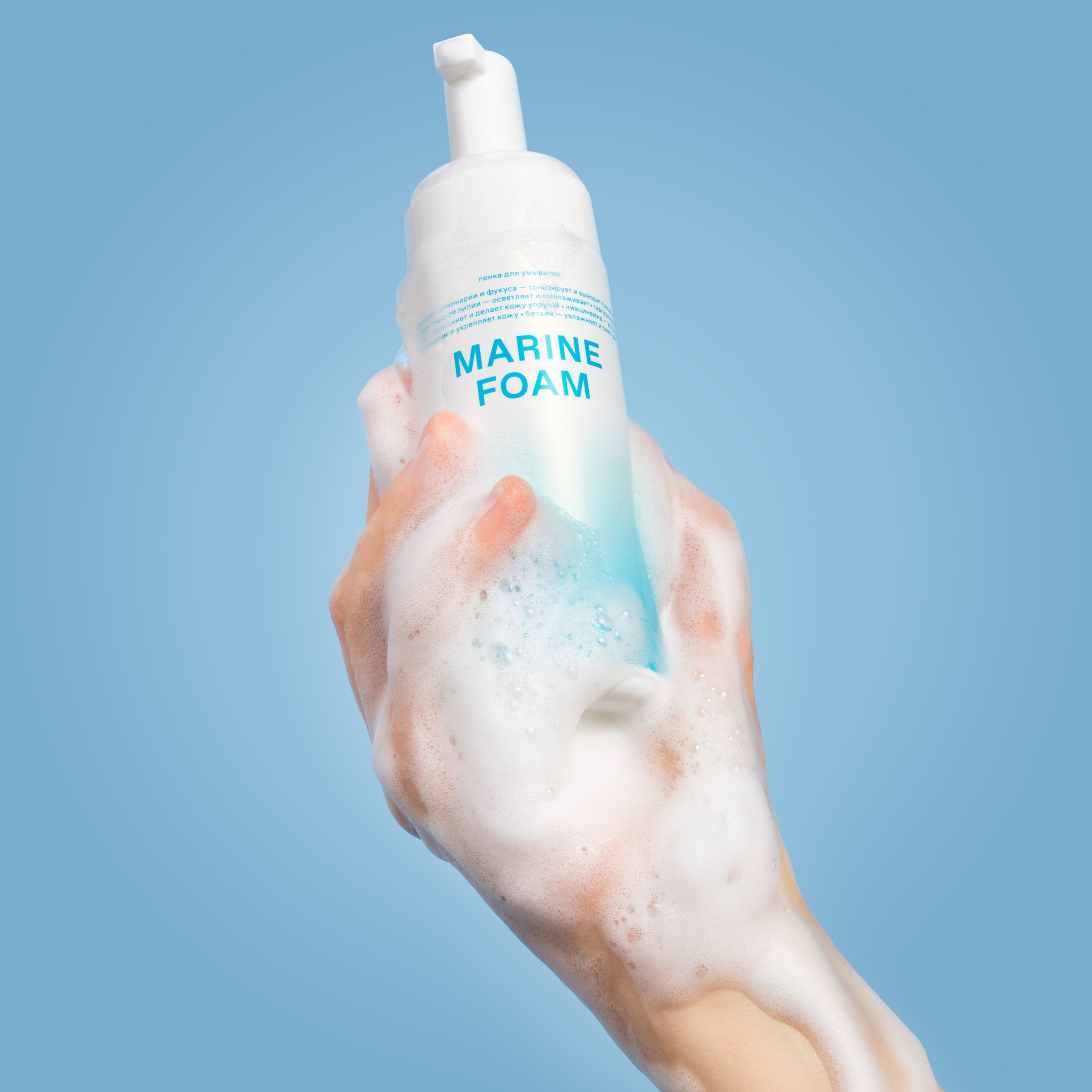 Предметное фото пенки для умывания с моделью рук на голубом фоне