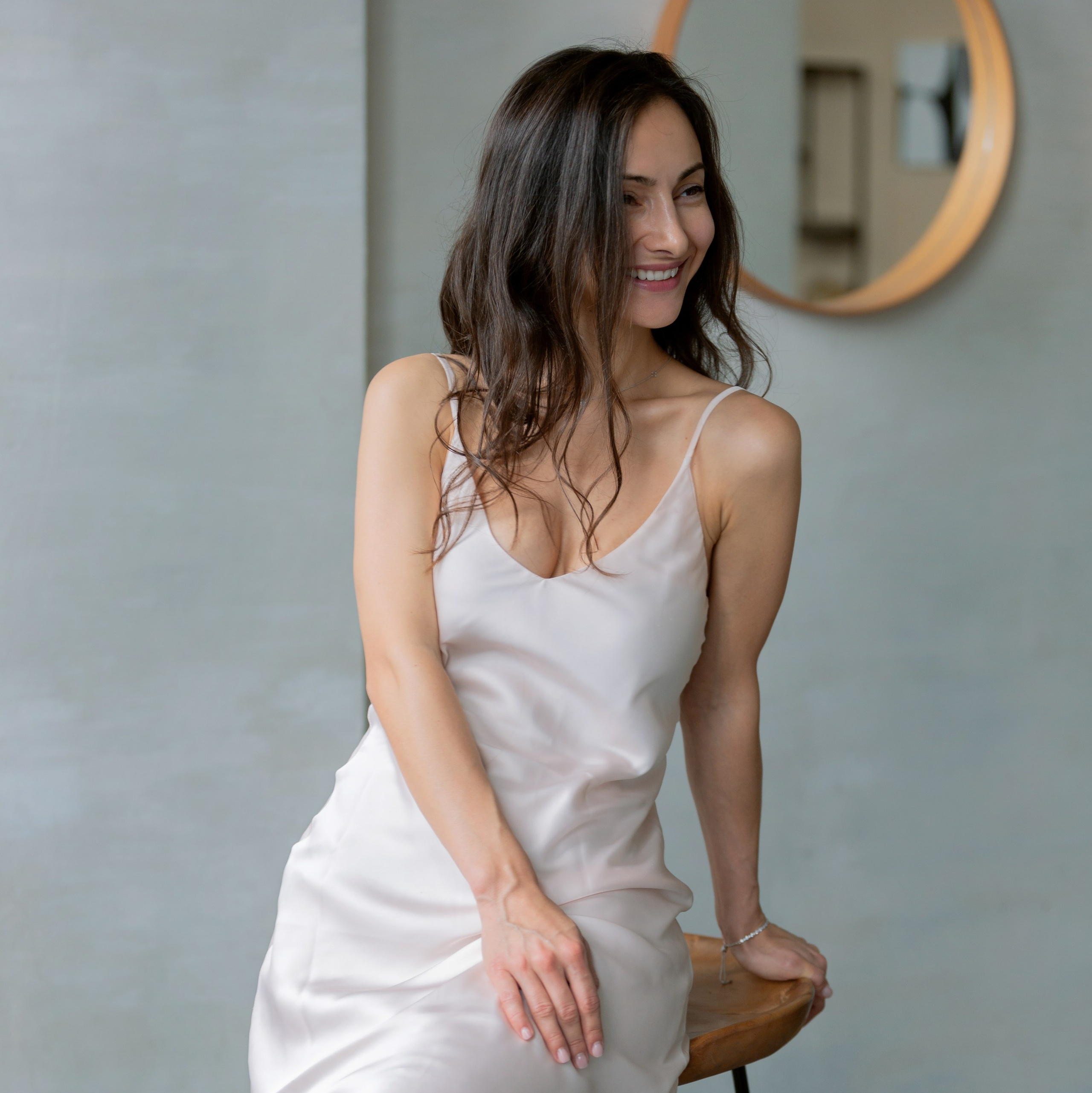 Девушка в белом платье нежно позирует у окна. Пример фотосессии в подарок для девушки.