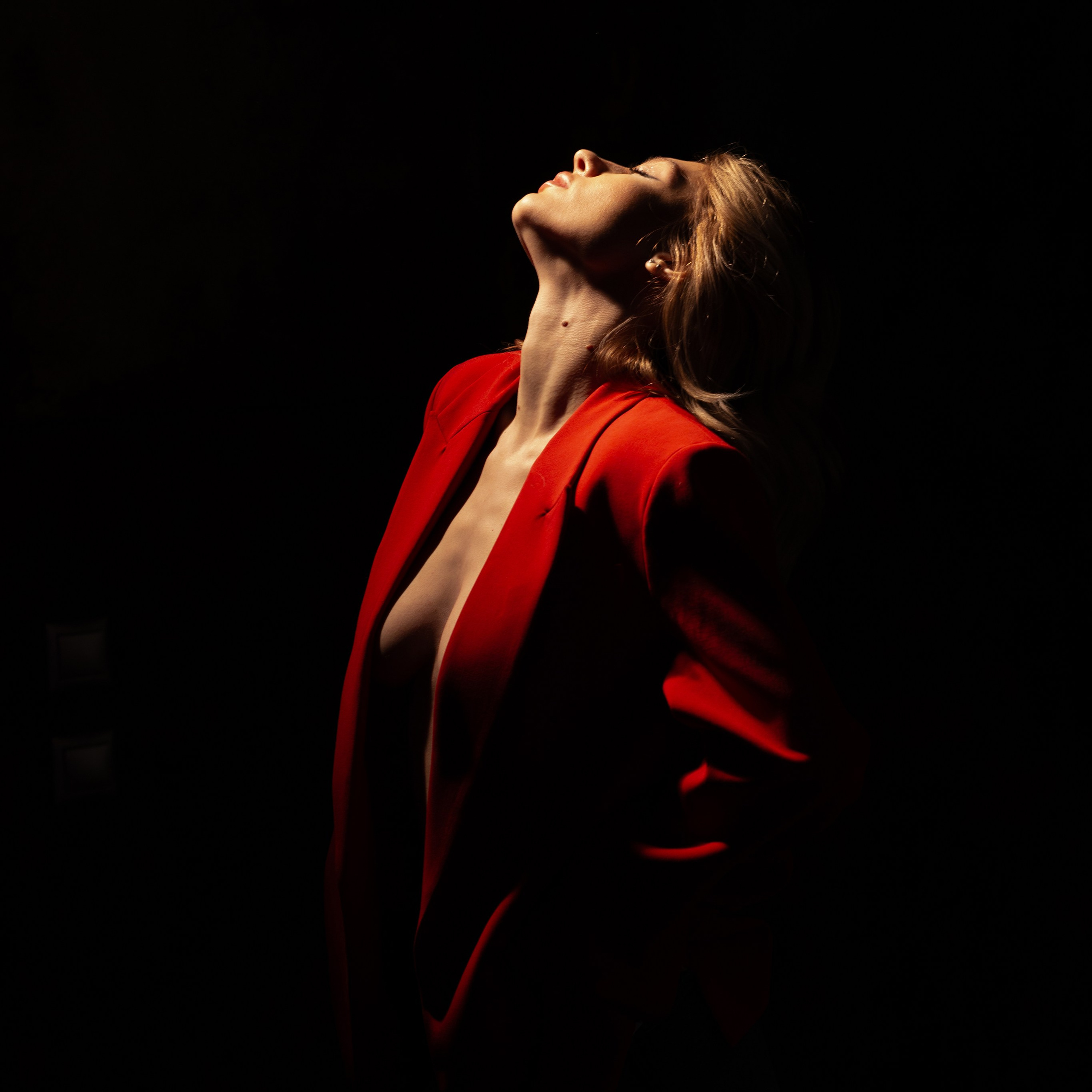 Драматичный силуэт девушки в красном платье на фоне глубокого чёрного цвета.