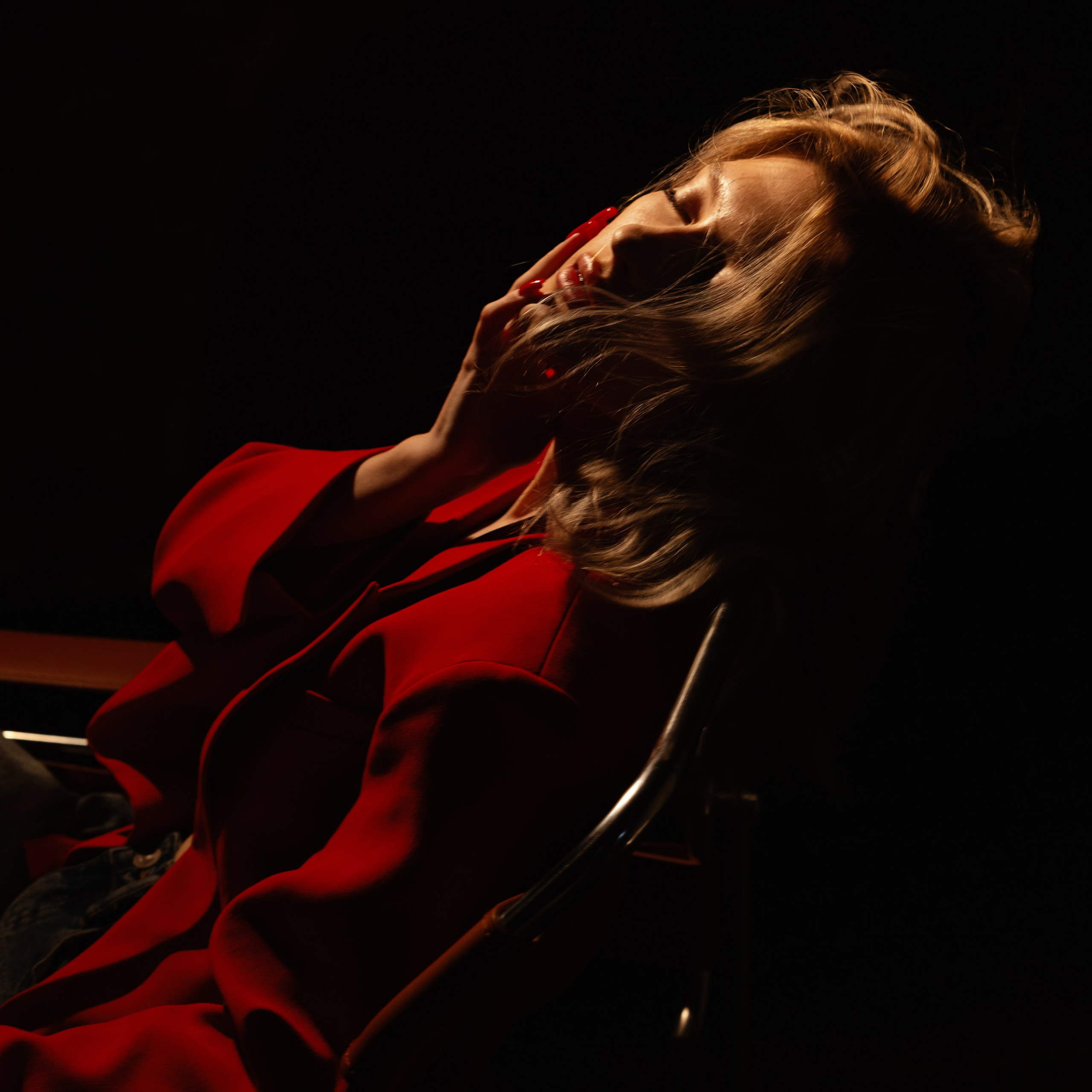Драматичный силуэт девушки в красном платье на фоне глубокого чёрного цвета.