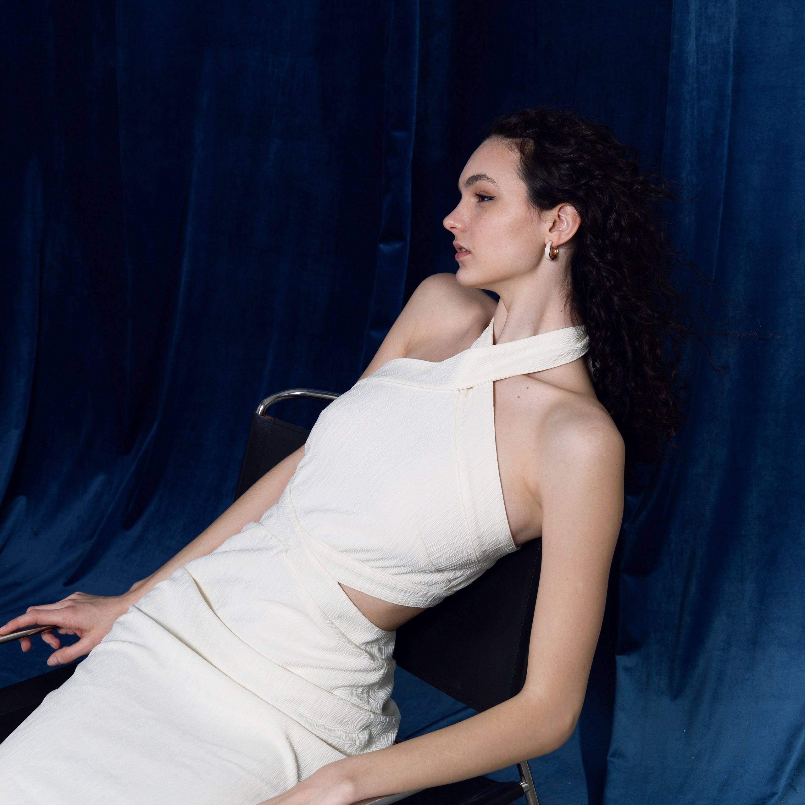 Индивидуальная съёмка: девушка в белом платье на фоне синей ткани.