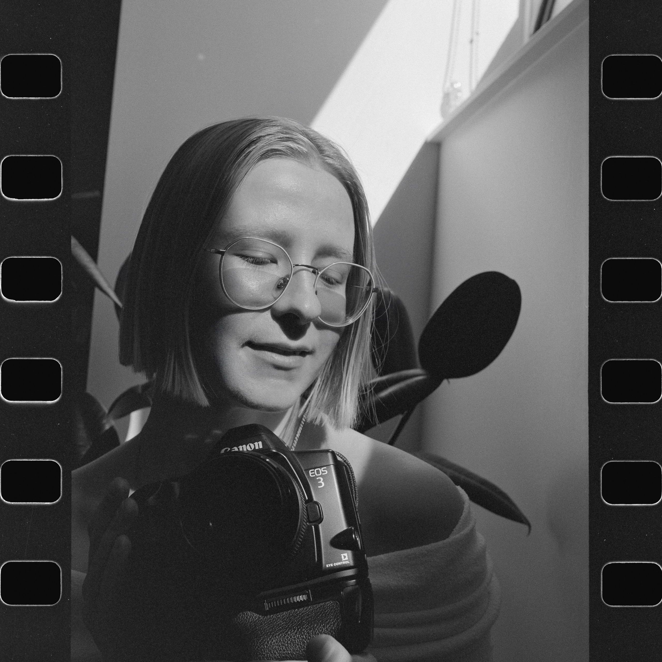 A black and white portrait of a film photographer in Los Angeles with her own film camera