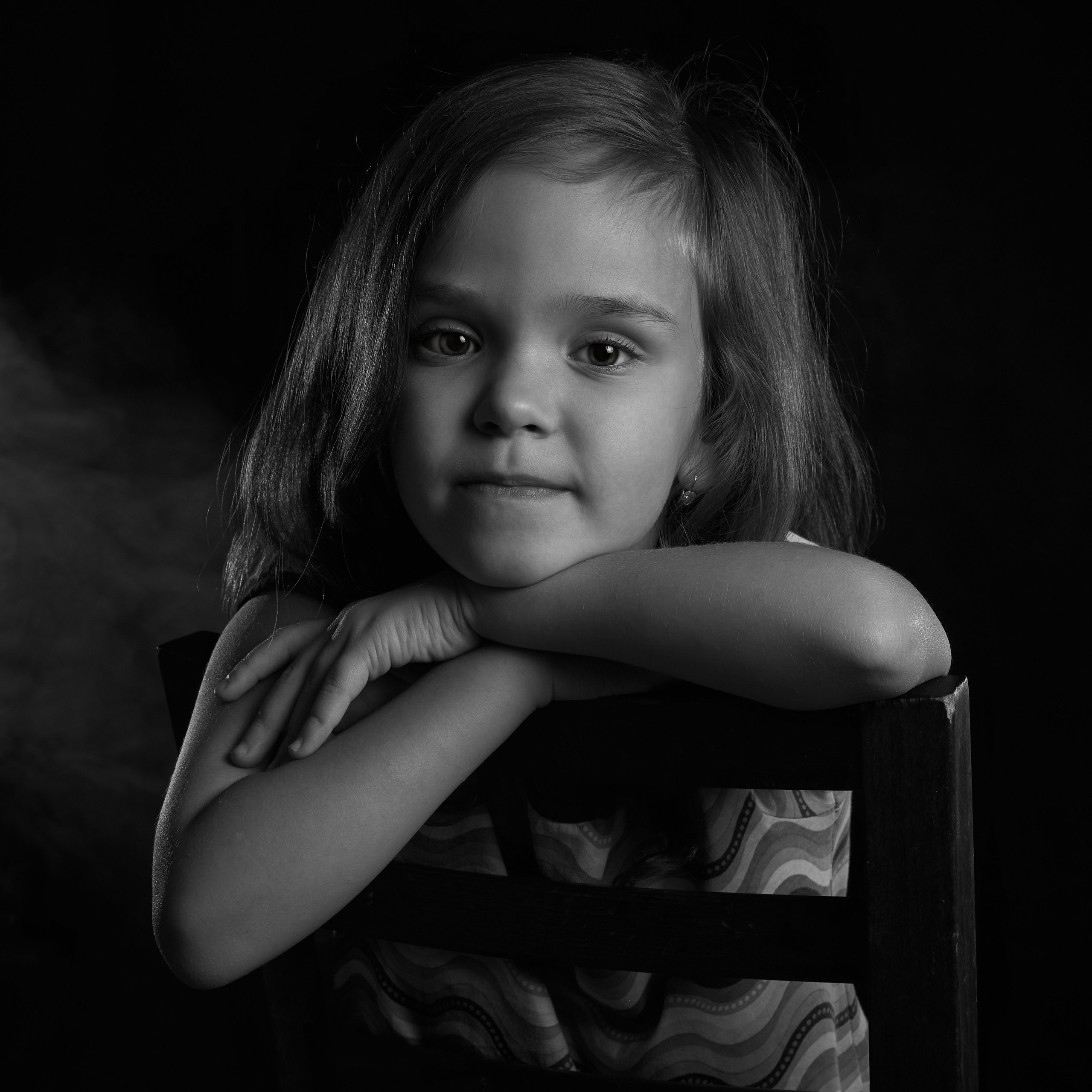 девочка опирается на спинку стула