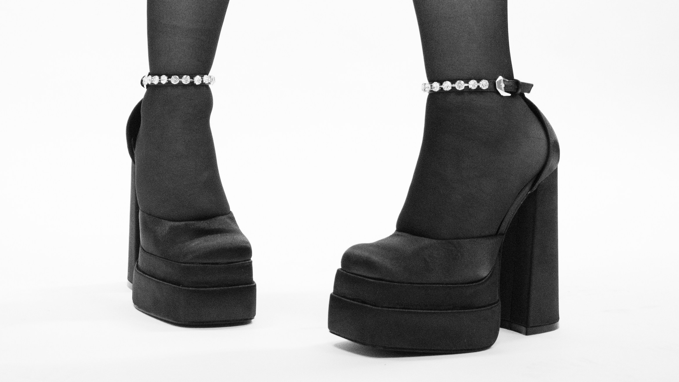 Черно-белый снимок ног девушки в туфлях на белом фоне