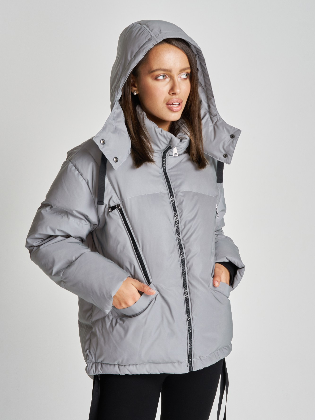 Модель девушка в серой куртке на фоне циклорамы