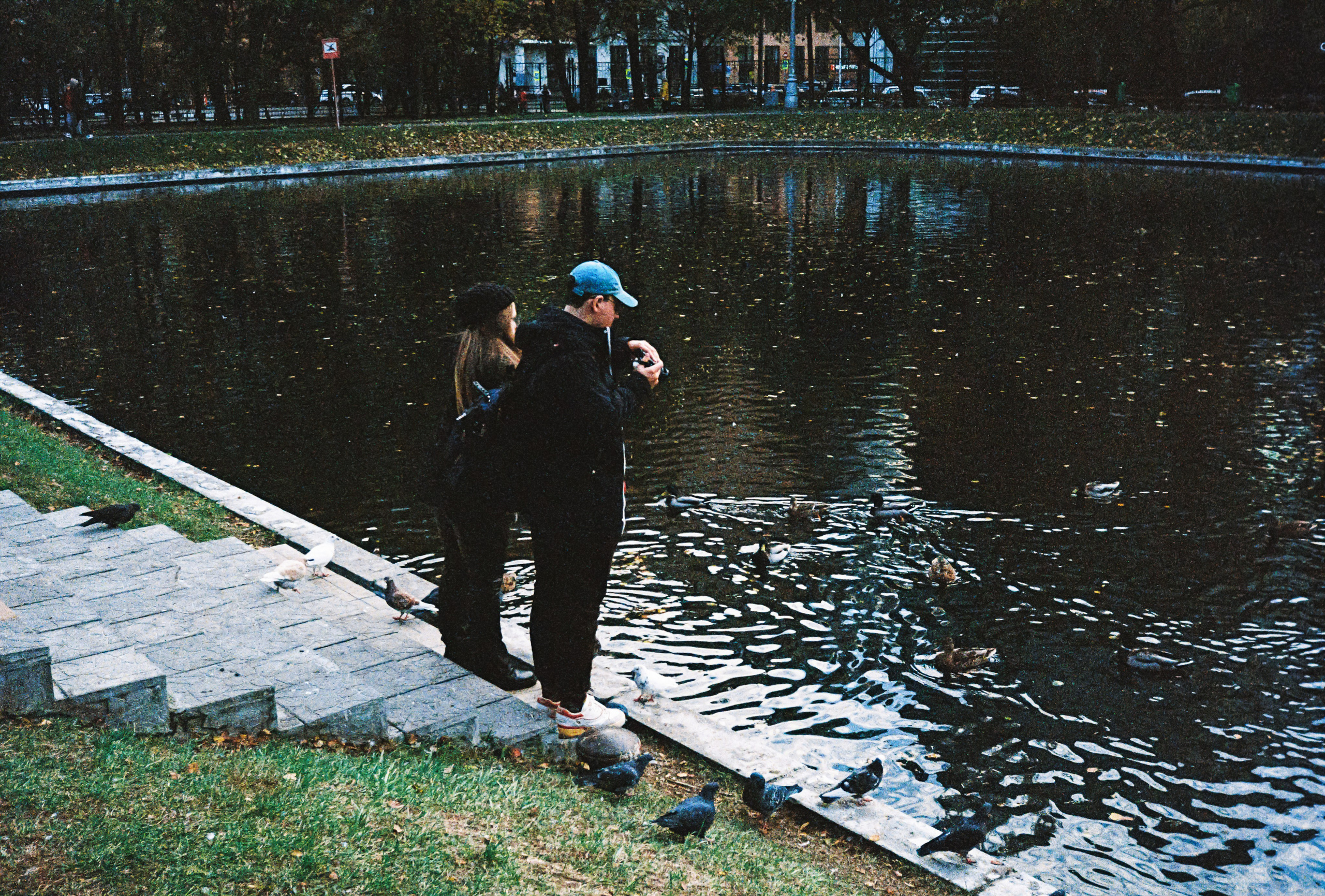 Пара кормит уток на пруду в парке Усадьба Трубецких