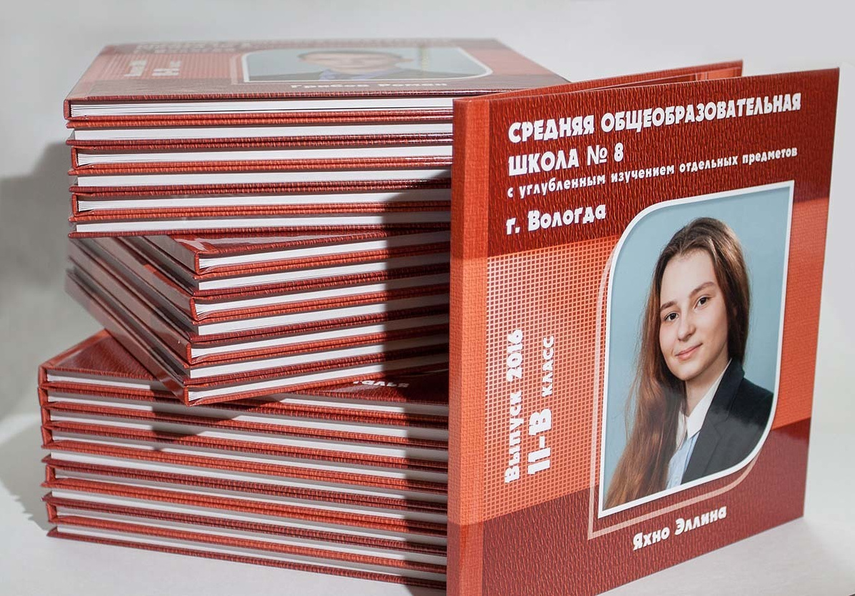 Выпускные оранжевые фотокниги в стопке и обложка с портретом выпускника 11 класса на сером фоне.