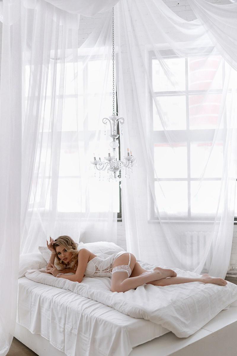 Будуарная фотосесия в белой кровати со шторами