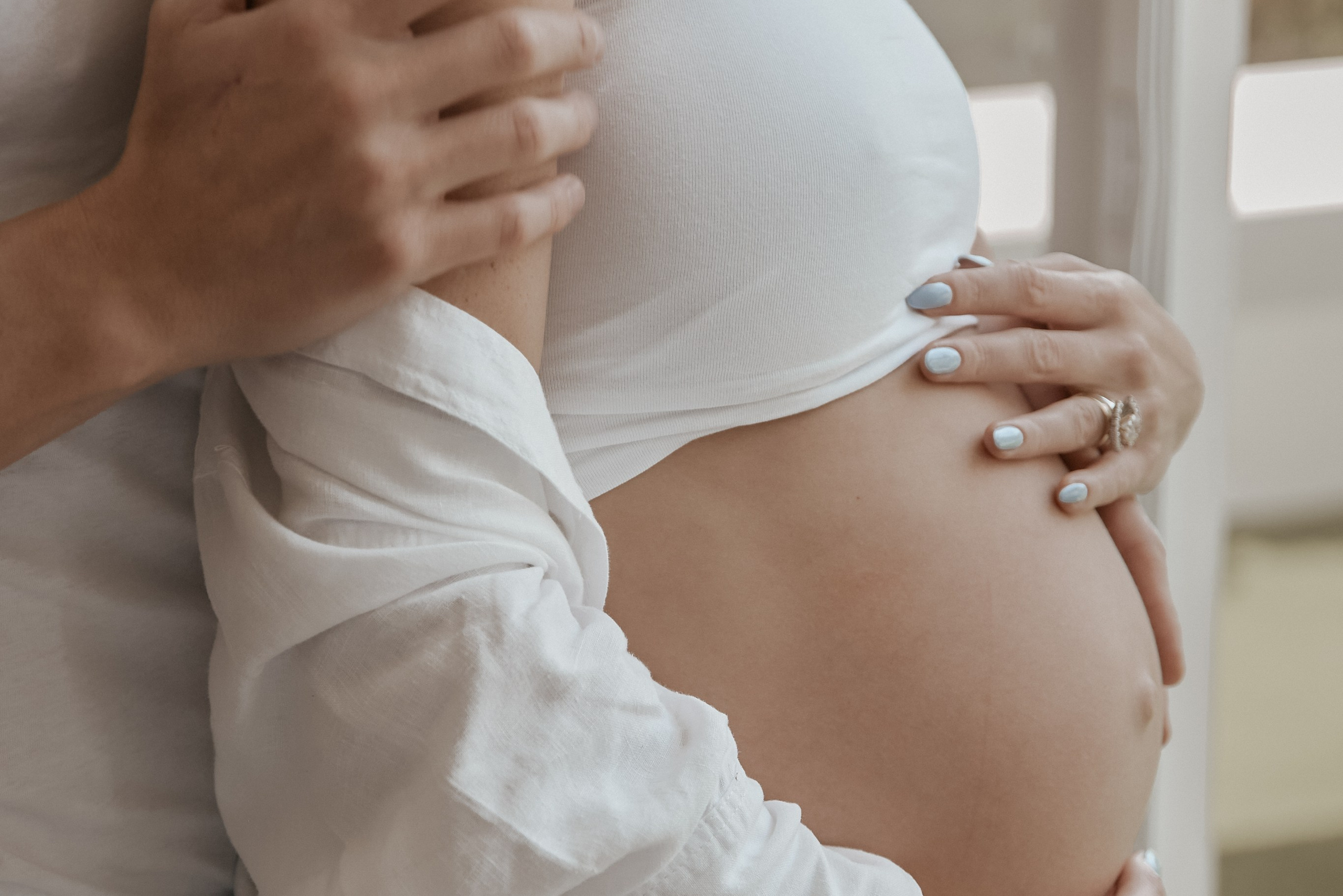 Close-up of a couple holding a pregnant woman's belly, emphasizing their loving connection and anticipation