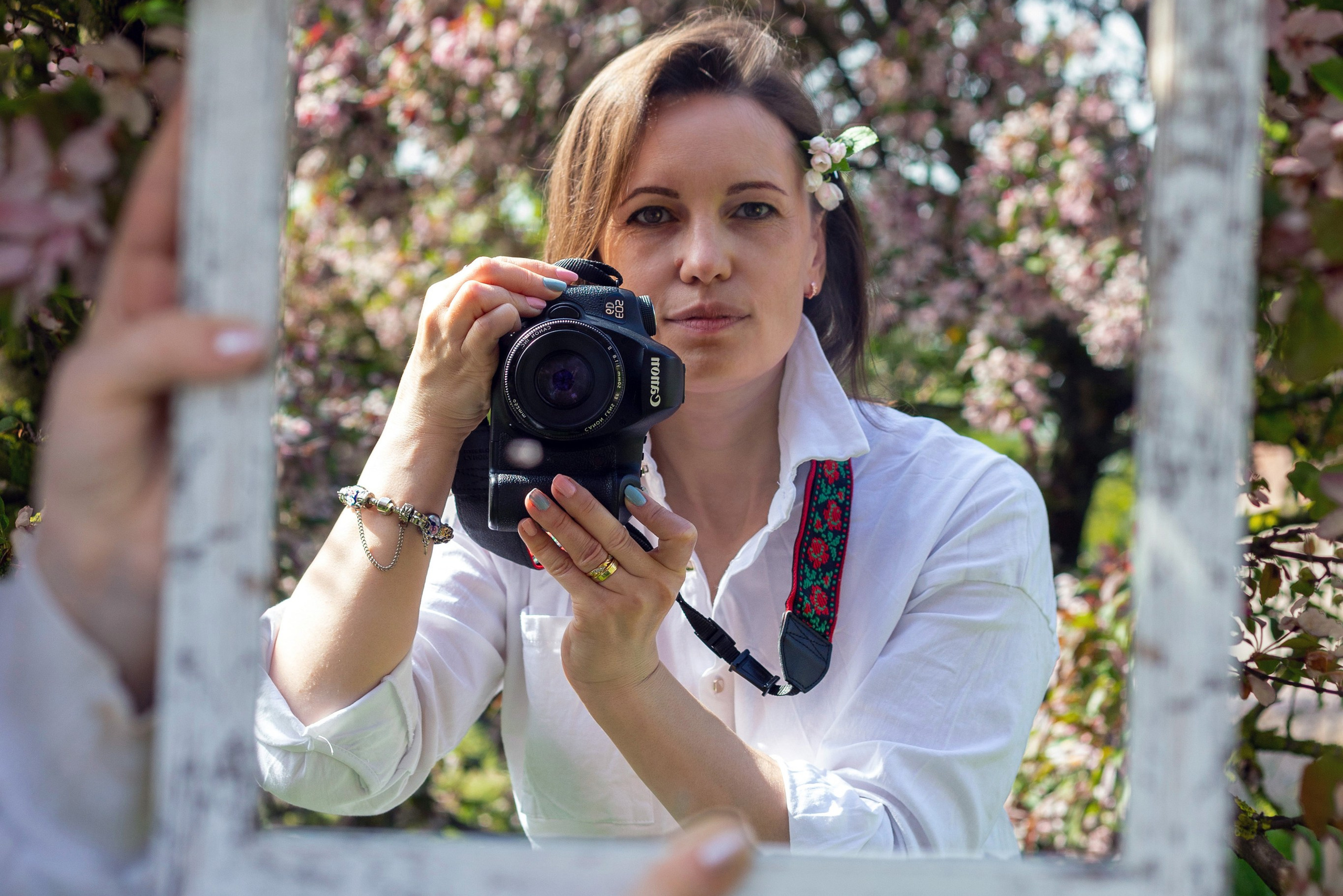 Фотограф с камерой и отражателем под цветущим деревом весной