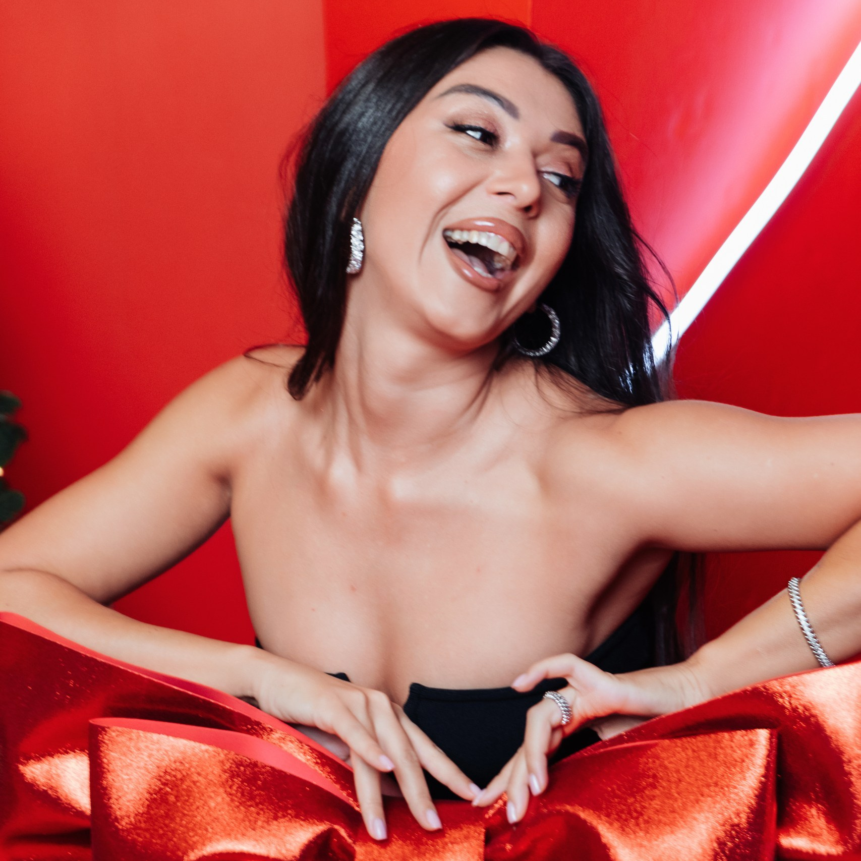 Новогодняя студийная фотосессия - девушка с большим бантом на красном фоне в новогодней фотосессии