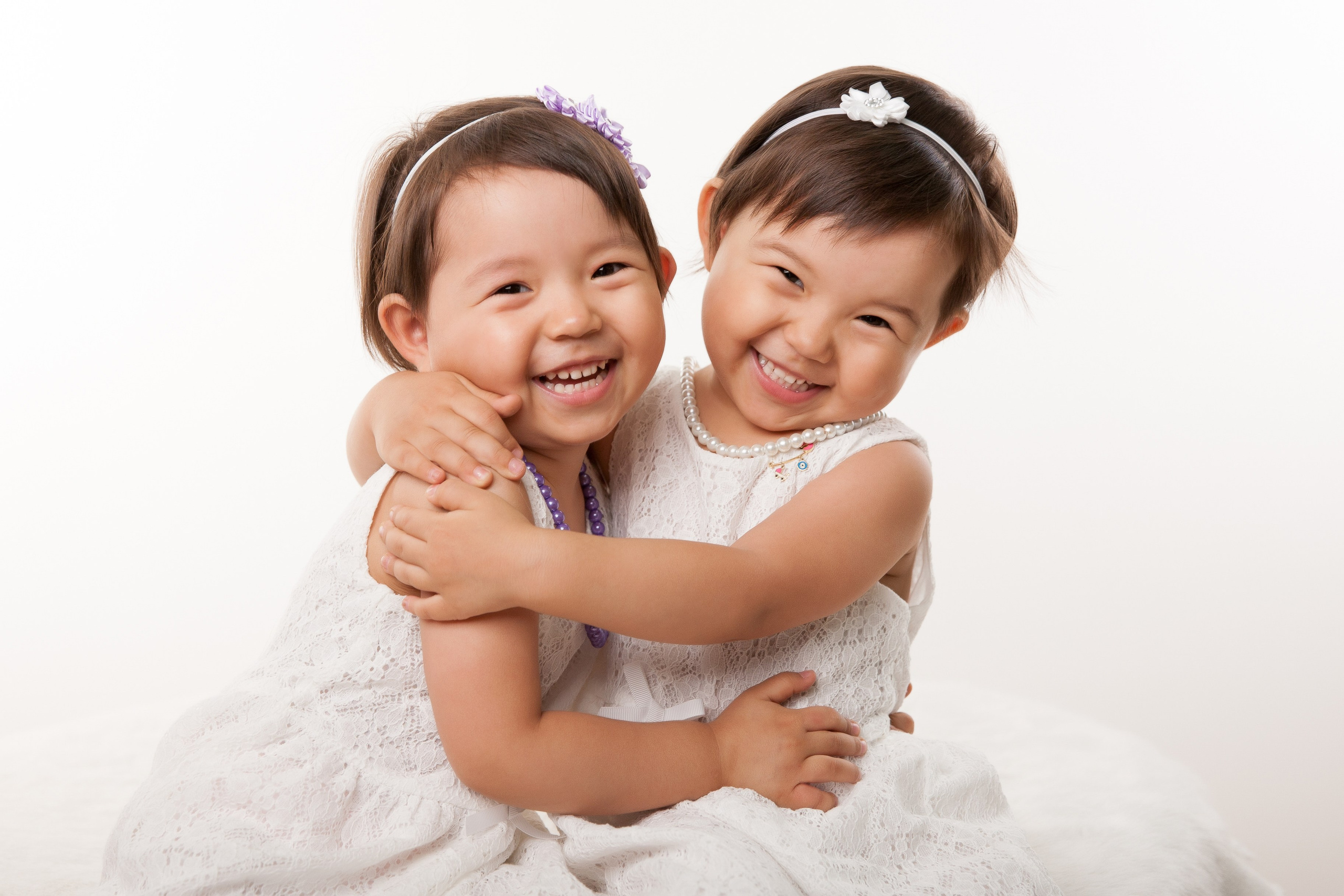 Детская фотосессия в студии Алматы. Девочки обнимают друг друга и смеются.