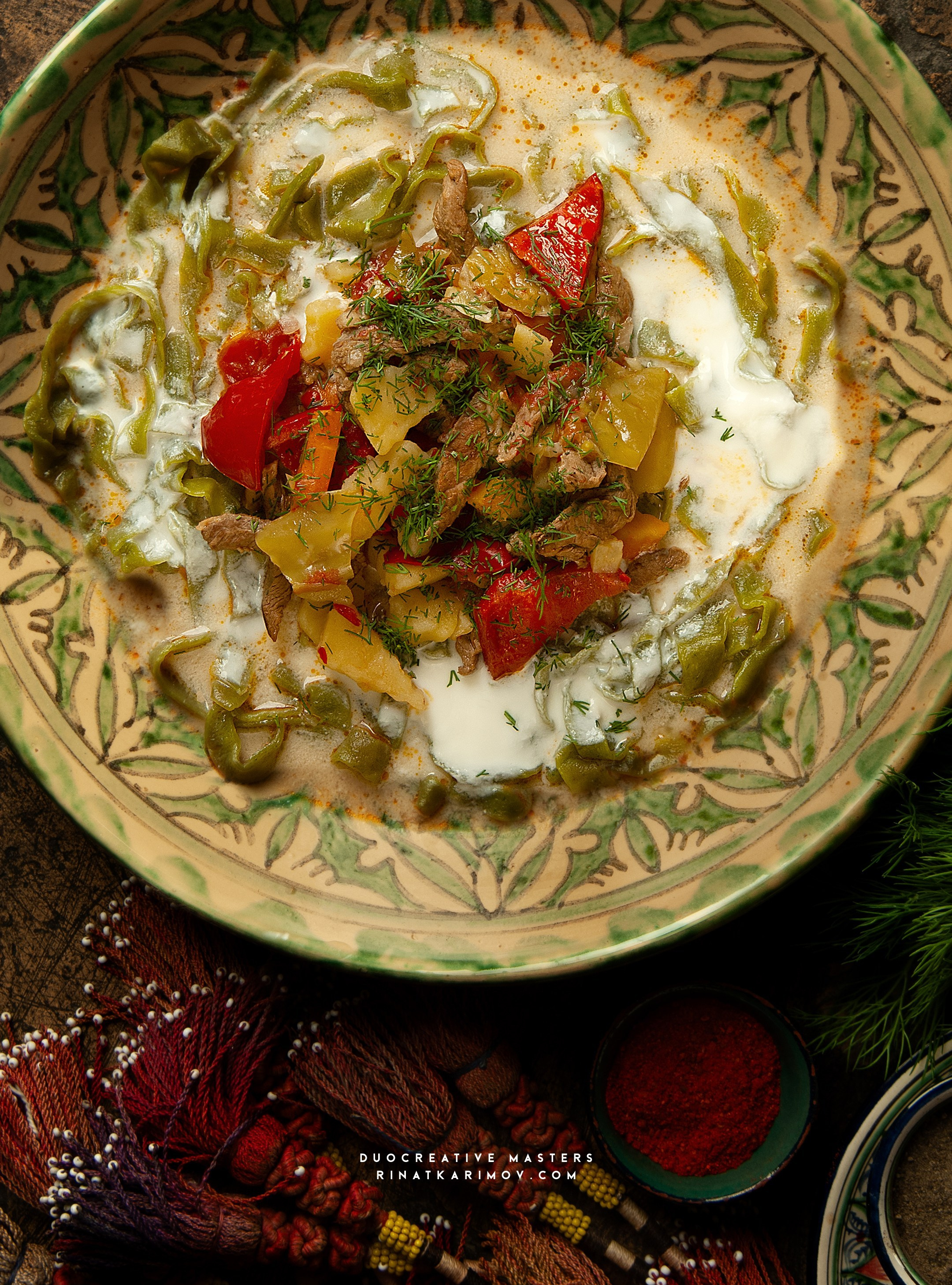 Национальное блюдо с зелёной лапшой, мясом и овощами в сливочном соусе. Аутентичная подача на керамической тарелке.