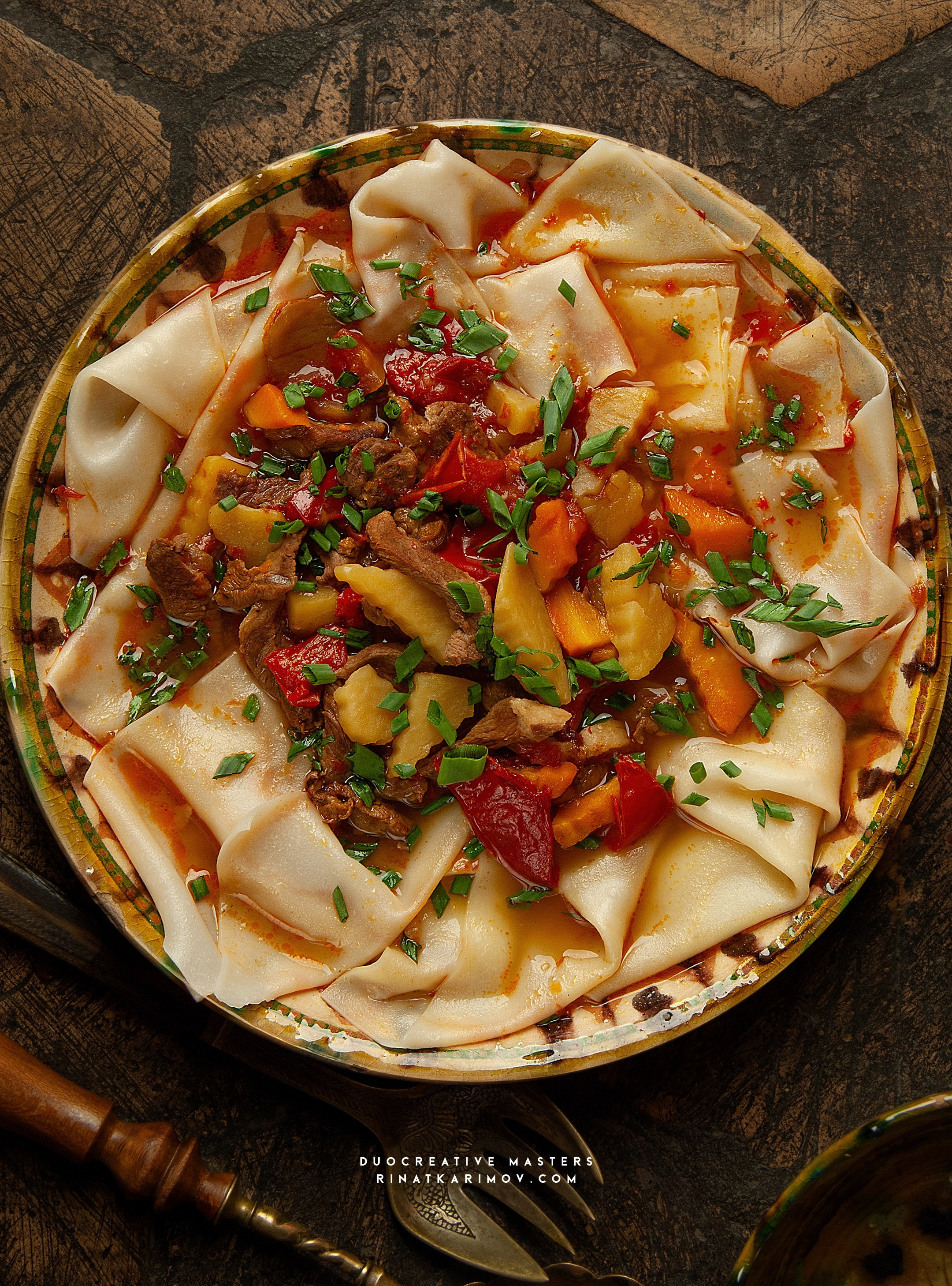 Традиционное блюдо с лапшой ручной работы, мясом и овощами в насыщенном соусе. Акцент на домашней подаче и деталях ингредиентов.