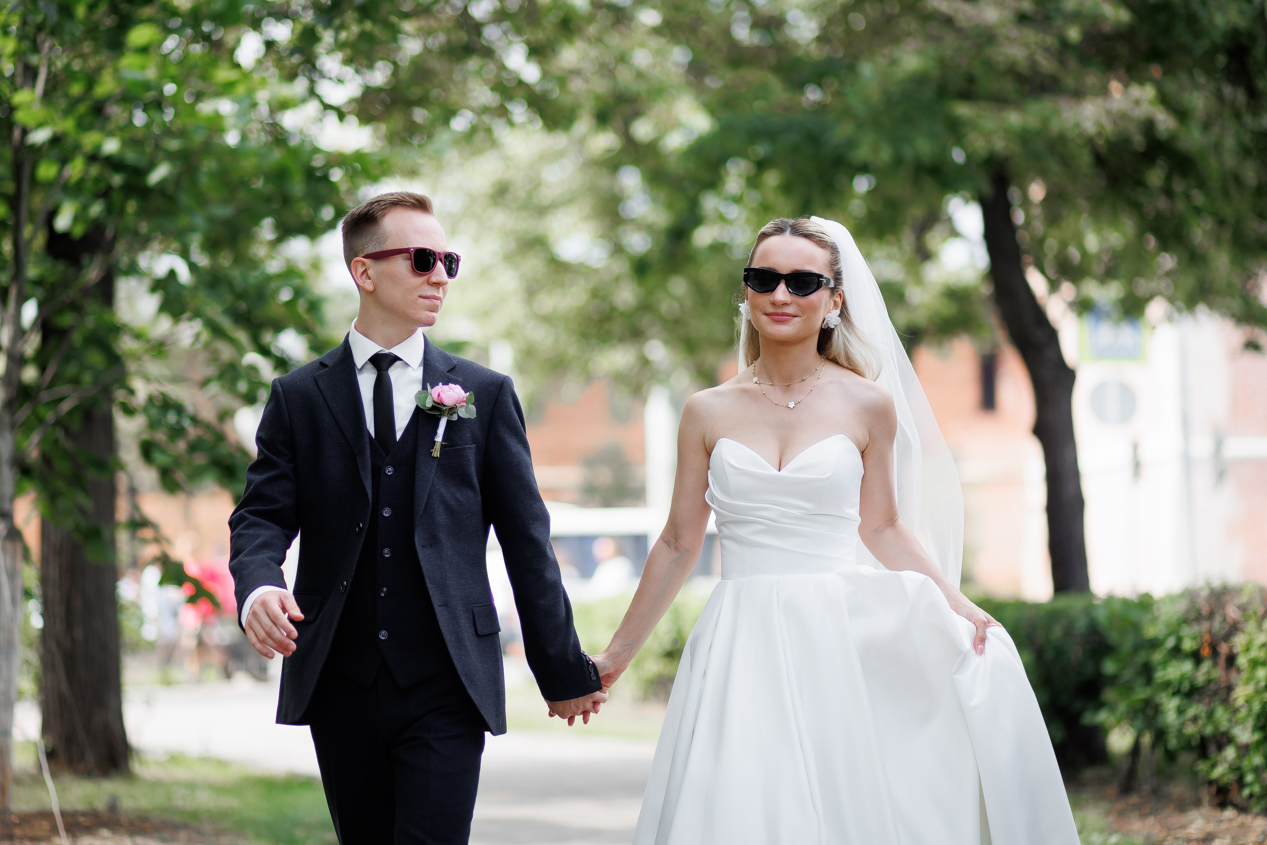 Молодожены весело идут по парку в очках