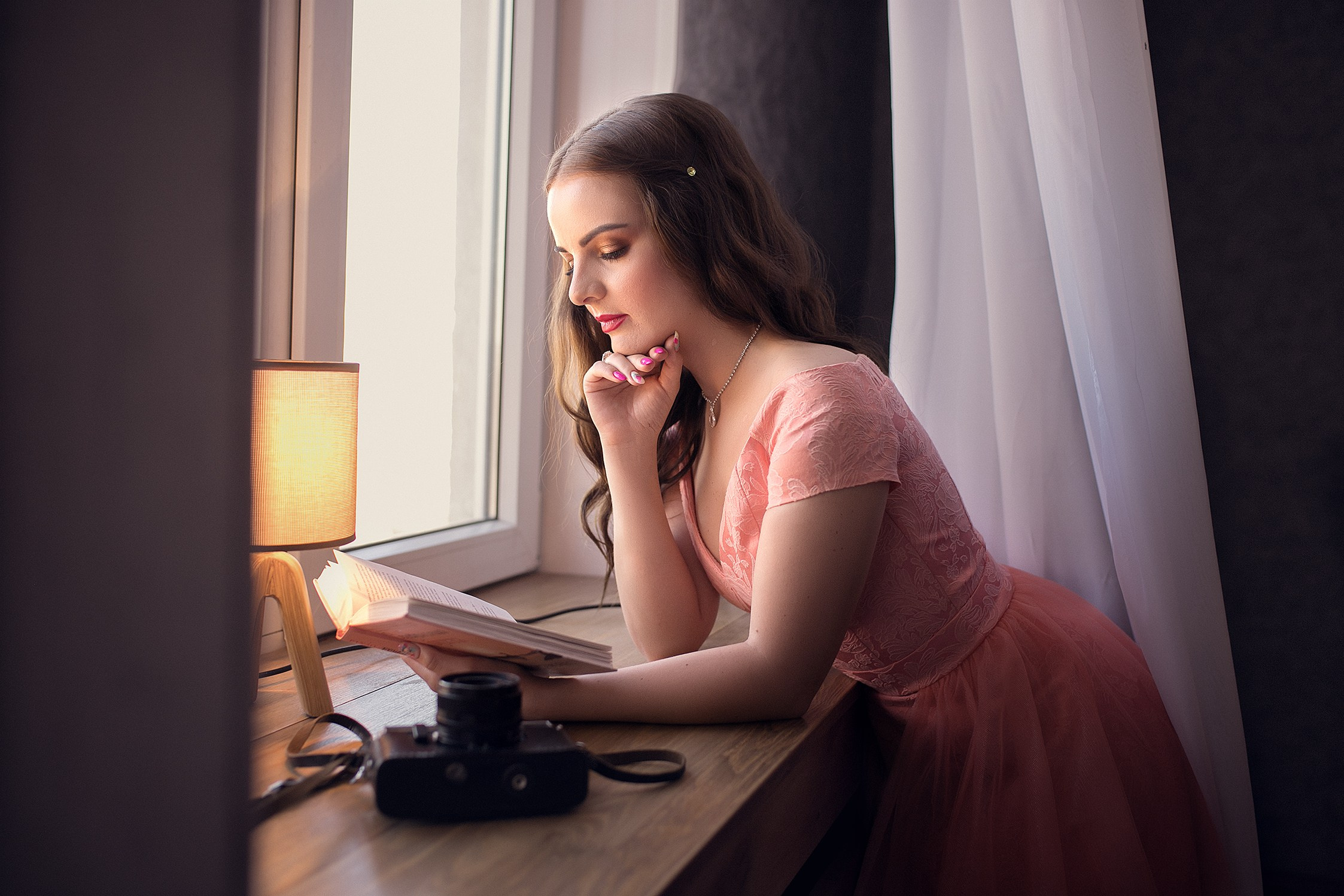 Девушка у окна читает книгу
