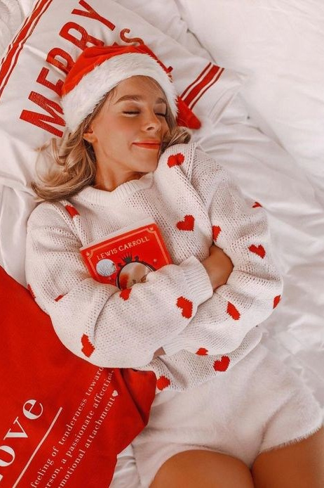 Девушка лежит на кровати в шапке Деда Мороза в бело-красной гамме