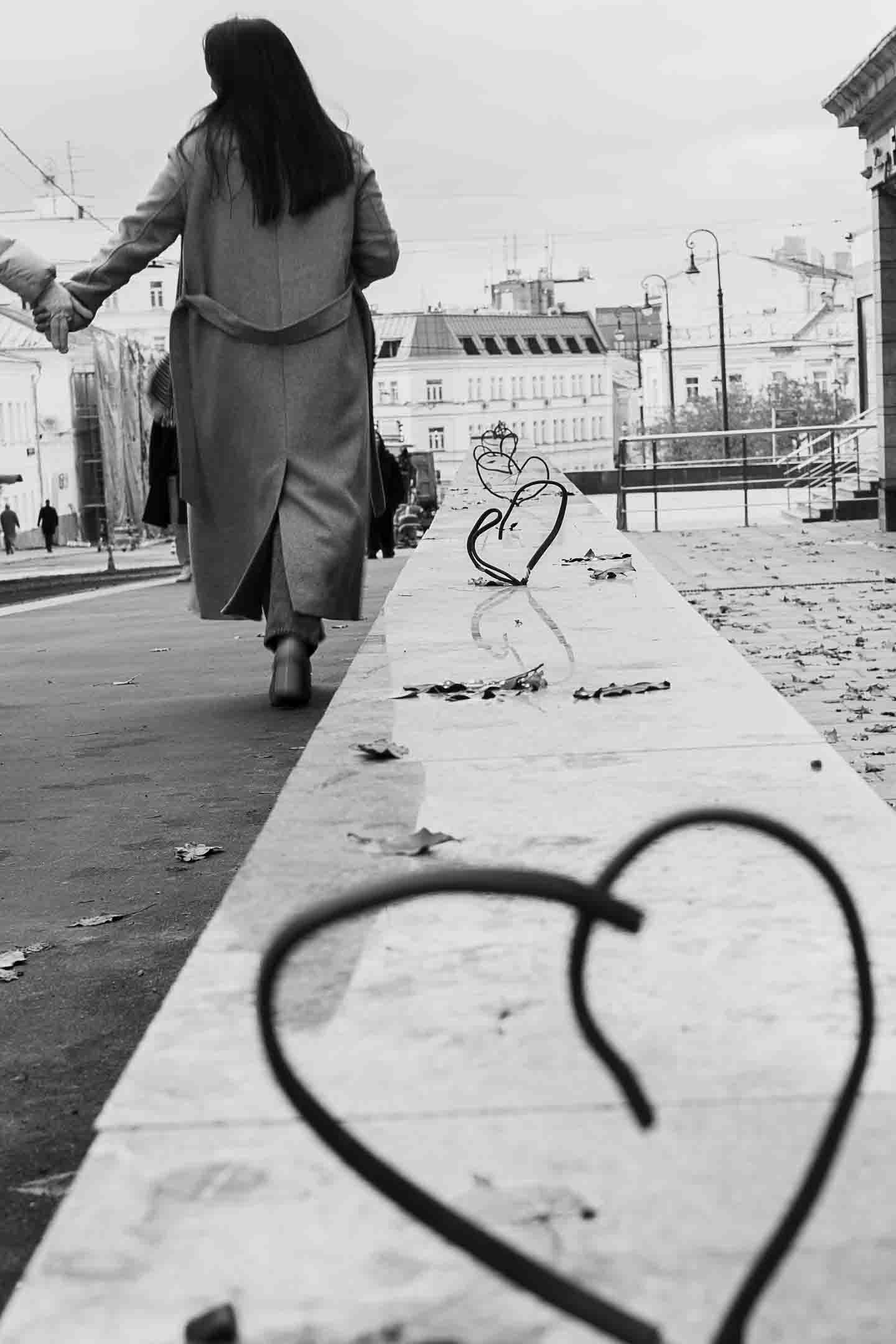 Фотография love-story. Девушка держит кого-то за руку и удаляется вдаль. Вдоль ее движения - сердца из проводов