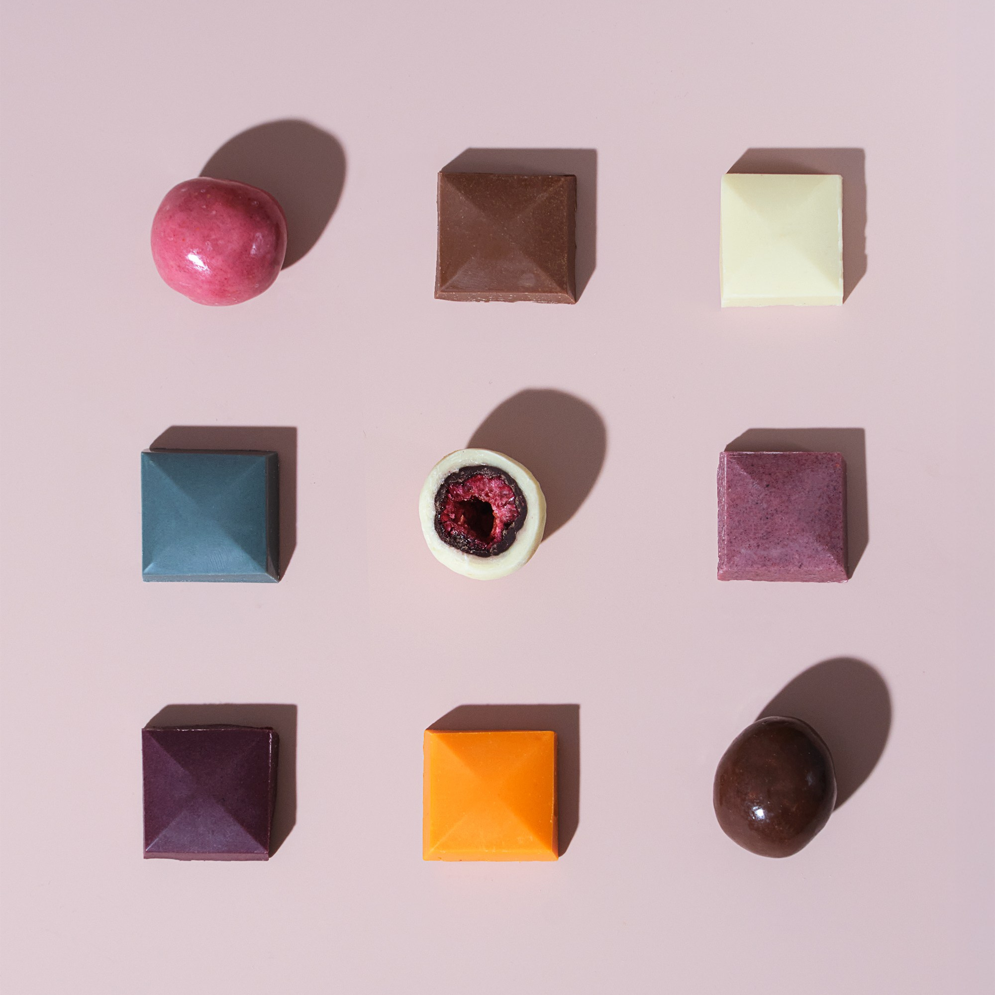 Графичный паттерн долек шоколада и шоколадных конфет на розовом фоне