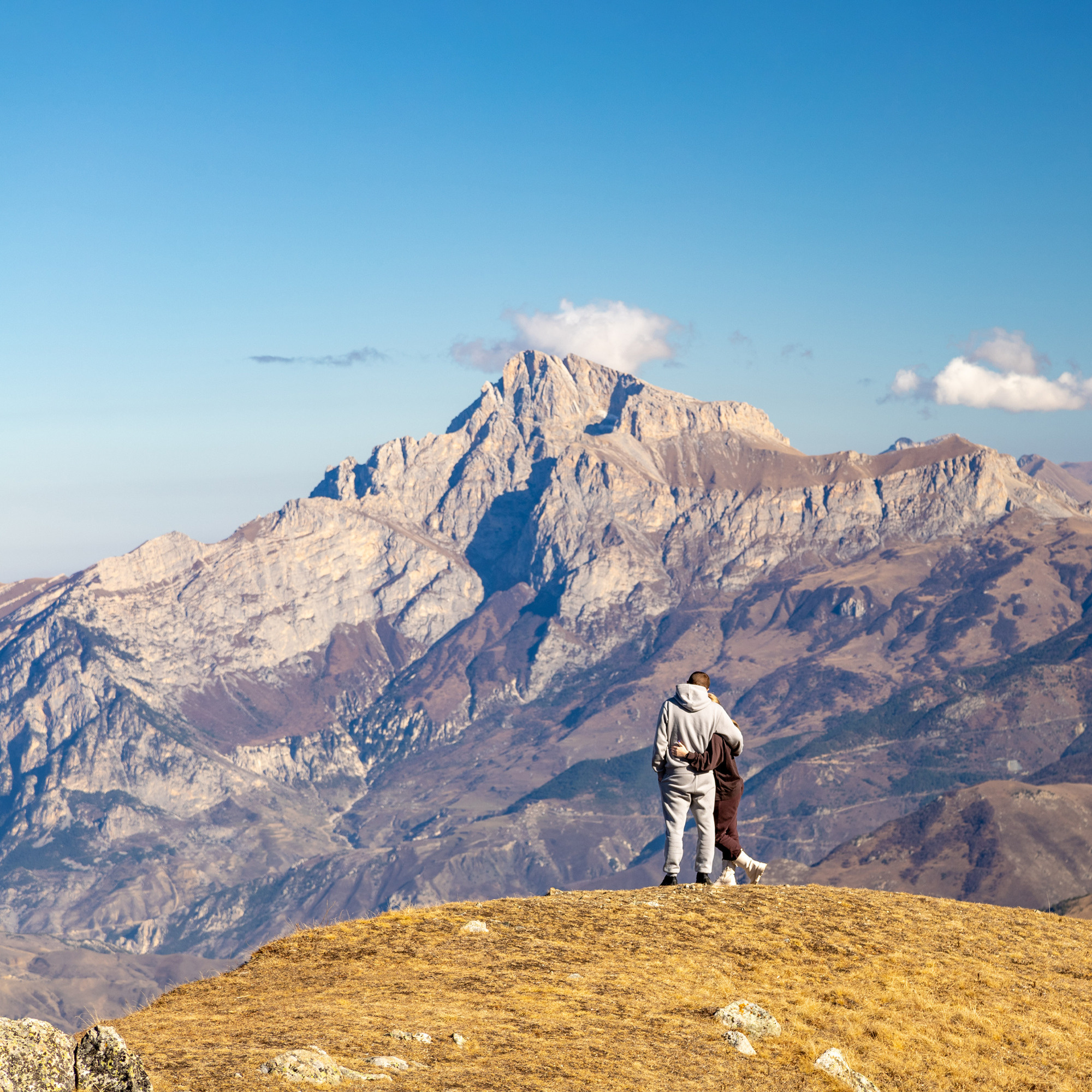 Влюбленная пара туристов на фоне горы Кариухох в Осетии, индивидуальный джип тур, осень в горах