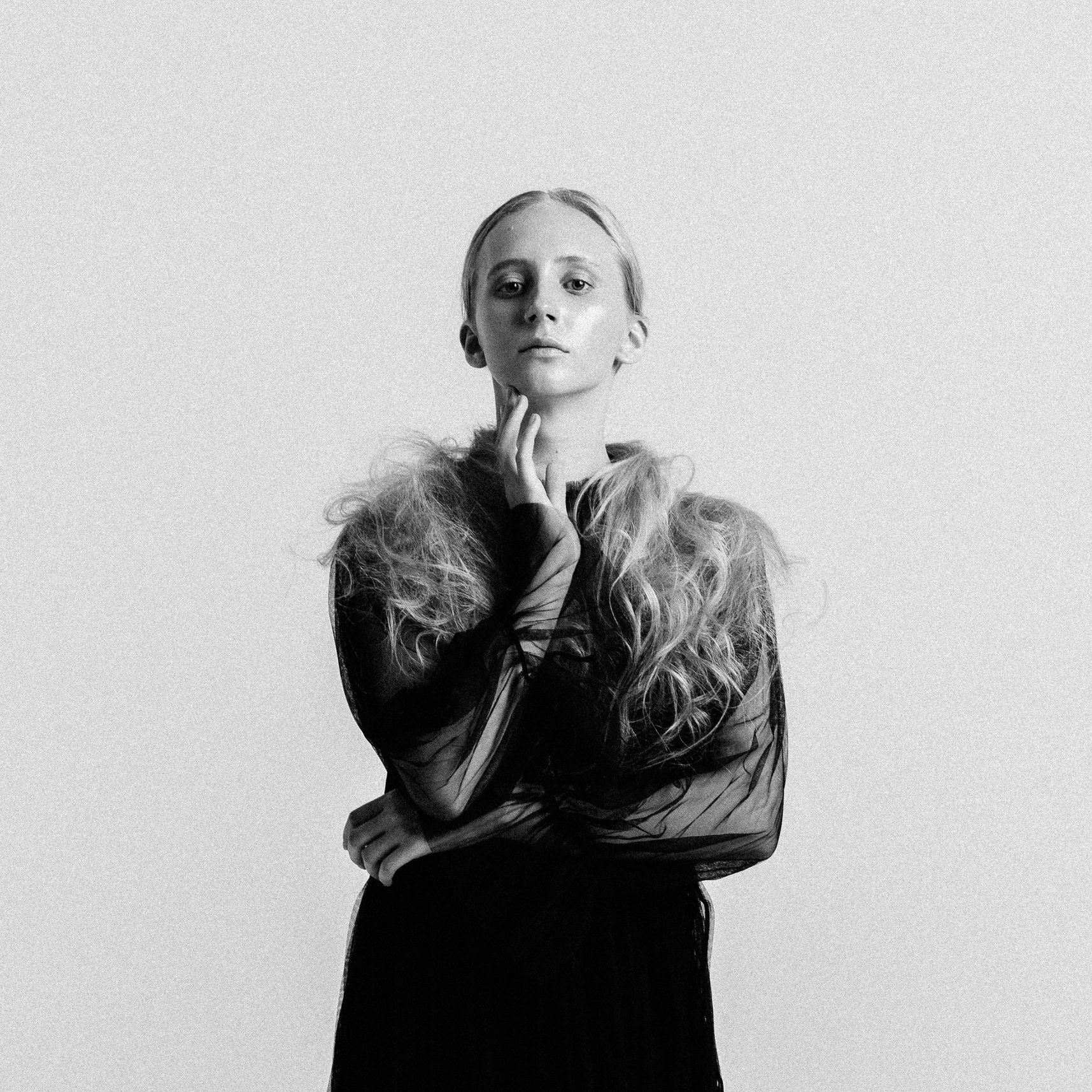 Студийный портрет женщины в строгом, но мягком образе. Съёмка на белом фоне.