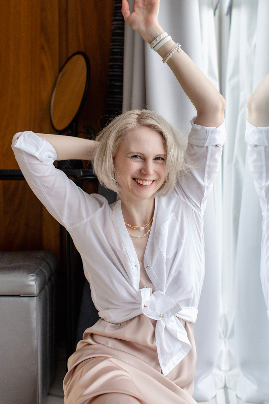 фотография красивой девушки блондинки, которая смеется, взмахнув руками вверх.