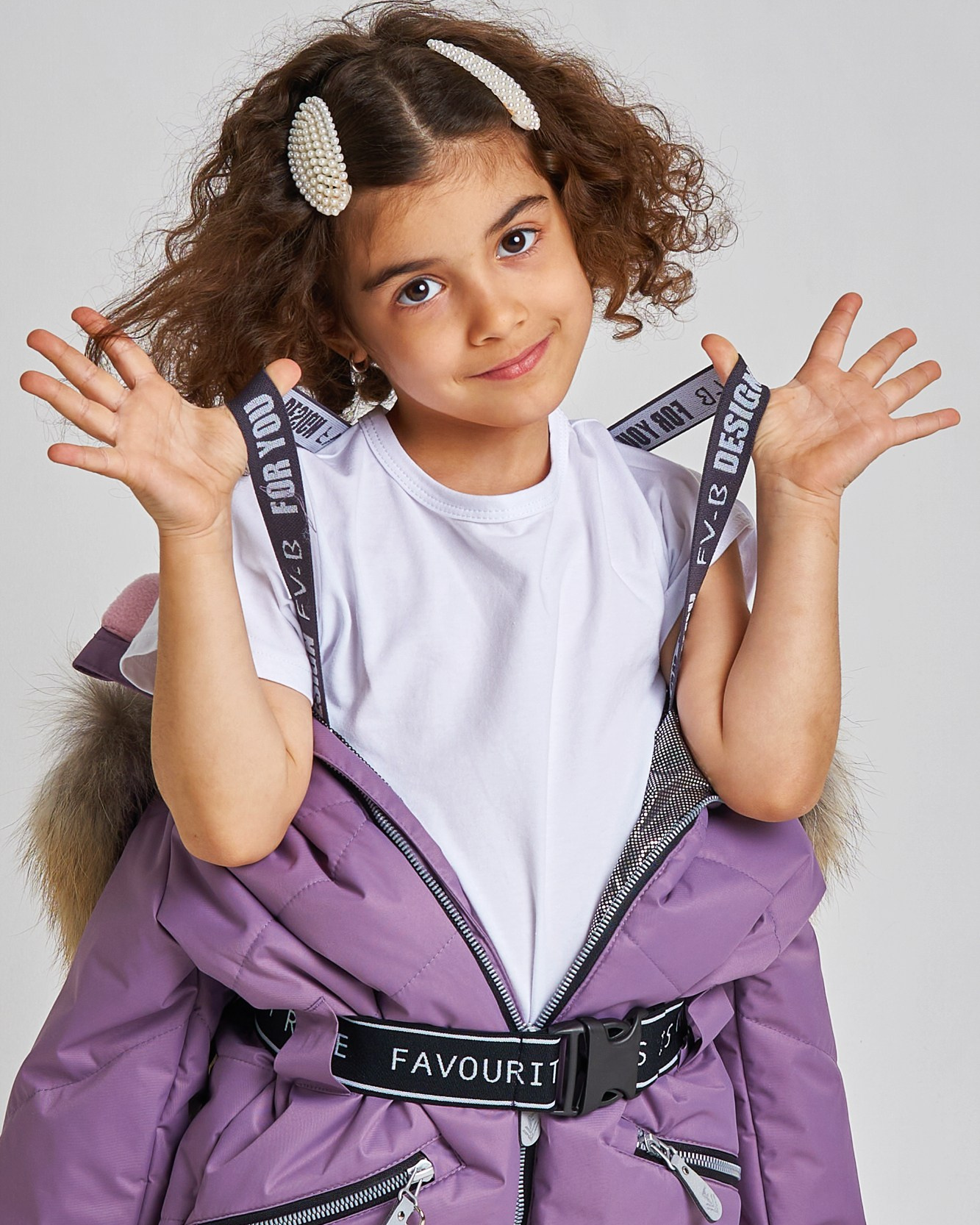 Ребенок модель оттягивает руками лямки комбинезона