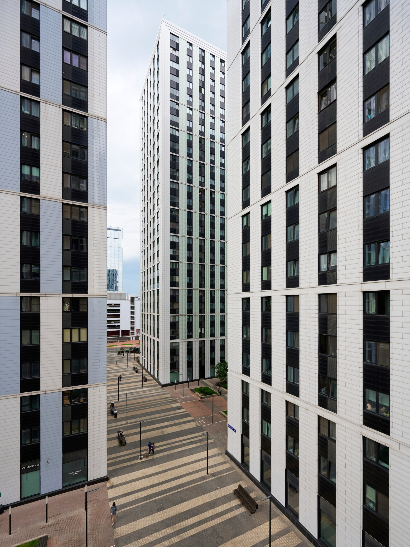 Двор между высотными корпусами, белые фасады, вертикальные линии