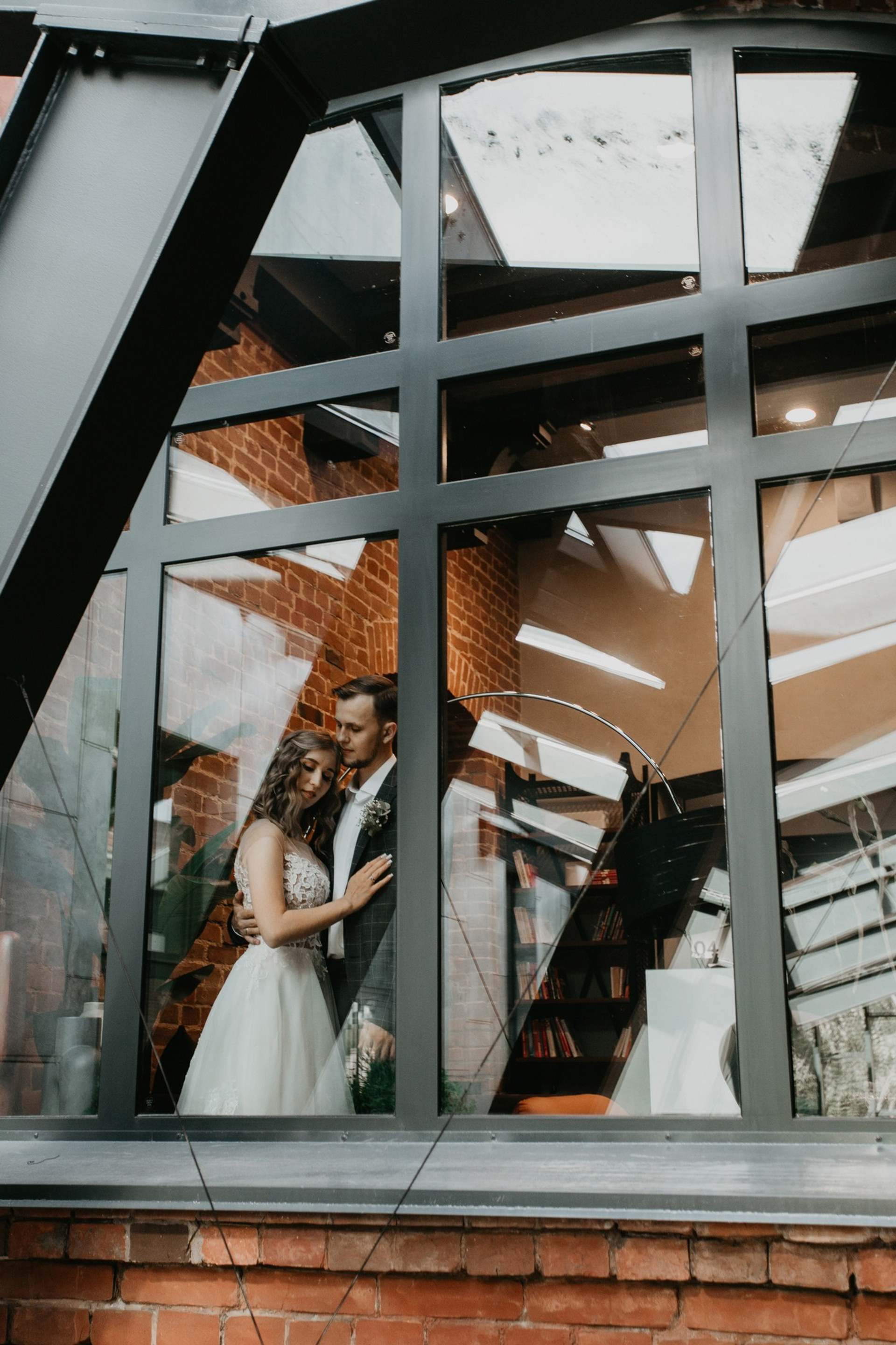 Свадебная фотосессия - пара обнявшись стоят у окна