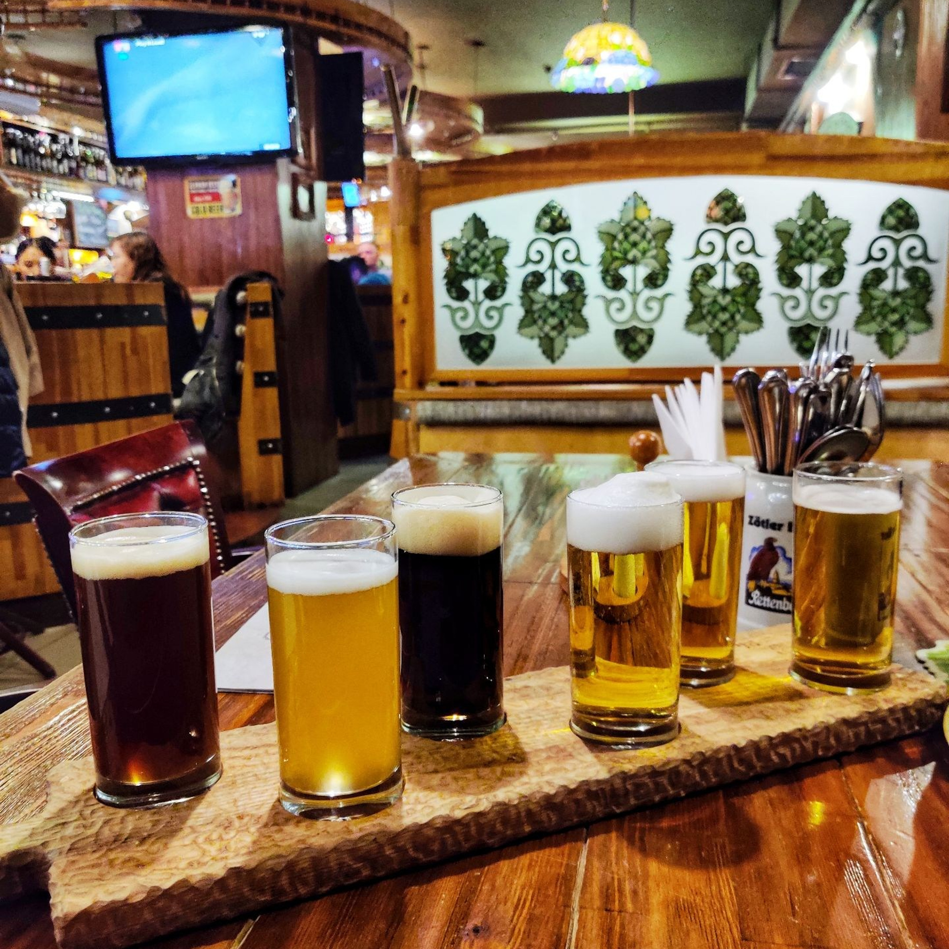 Дегустационный сет из шести сортов пива на деревянной доске в пивном баре