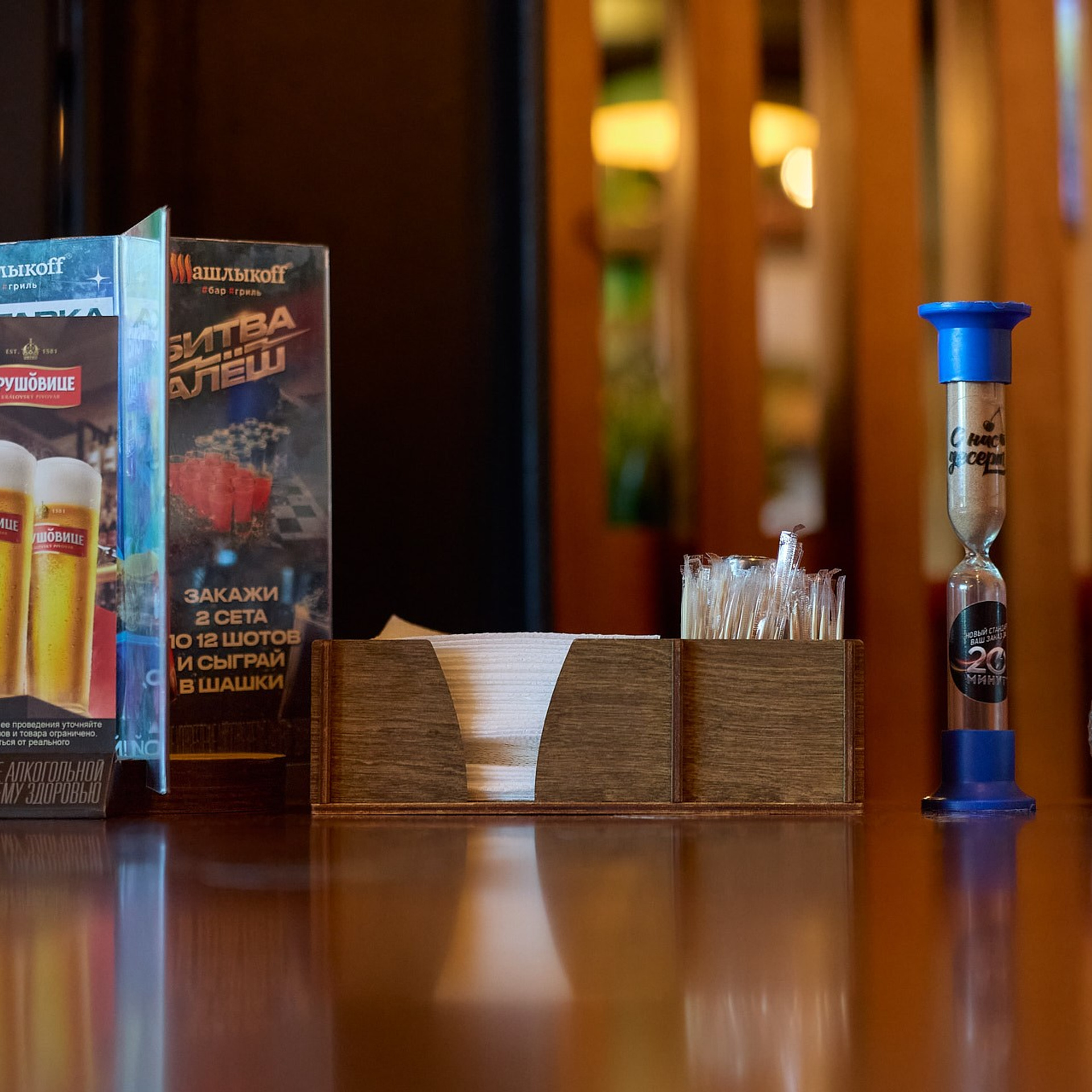 Часть интерьера кафе Шашлыкофф, салфетки, приправы и зубочистки на столе в полумраке.