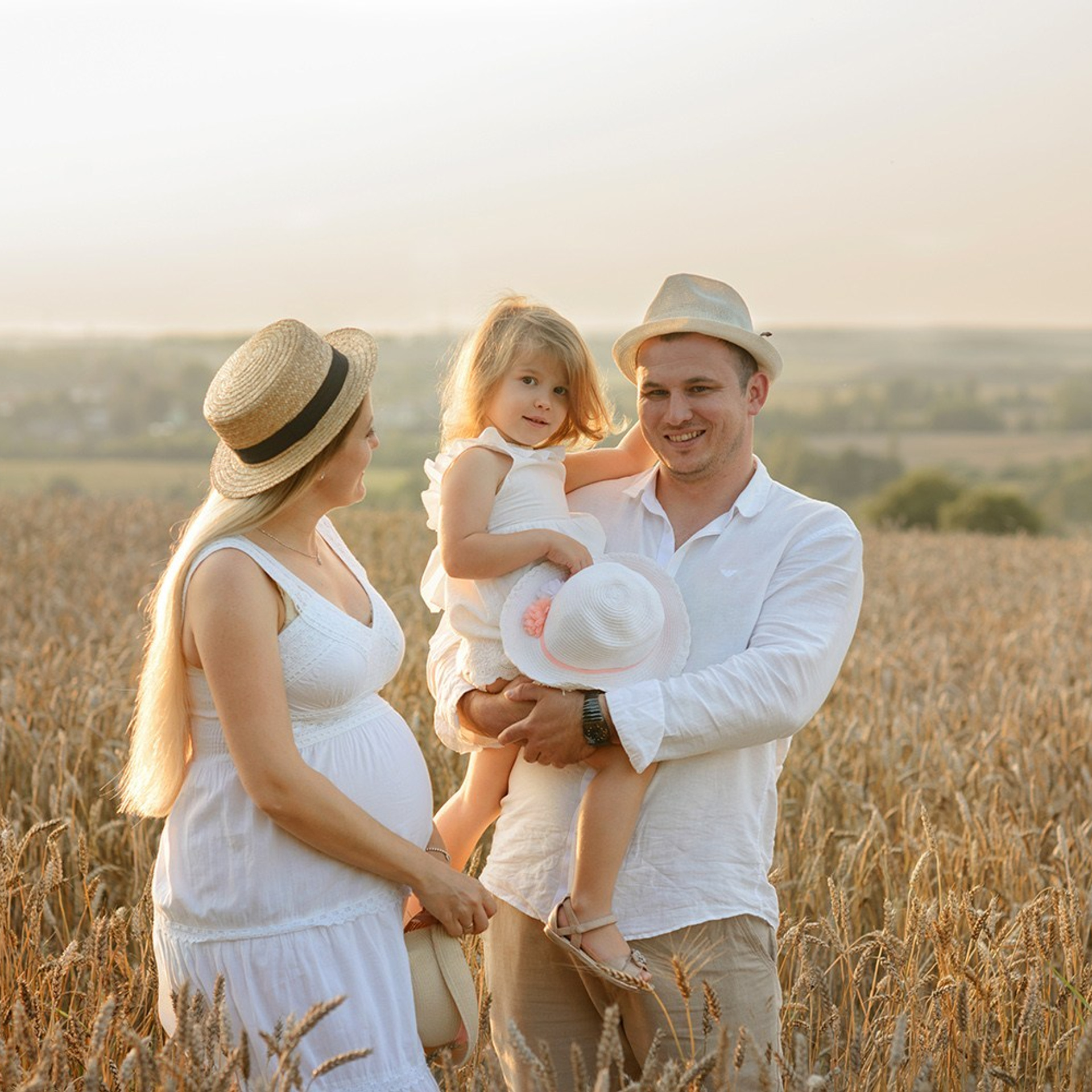 Photo shoot of a family with a pregnant woman and child at sunset