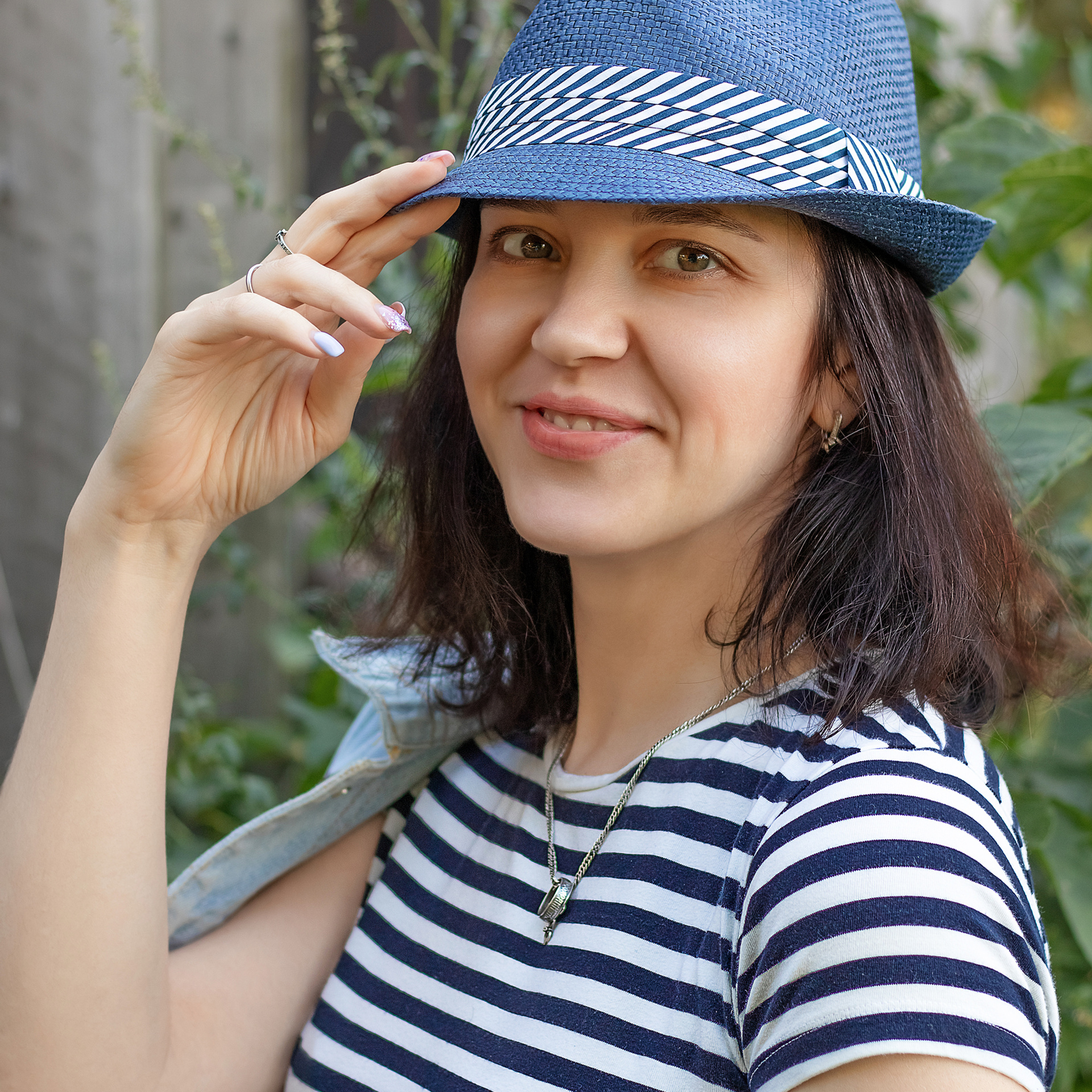 Фотография девушки в соломенной шляпе джинсового цвета и полосатой футболке.