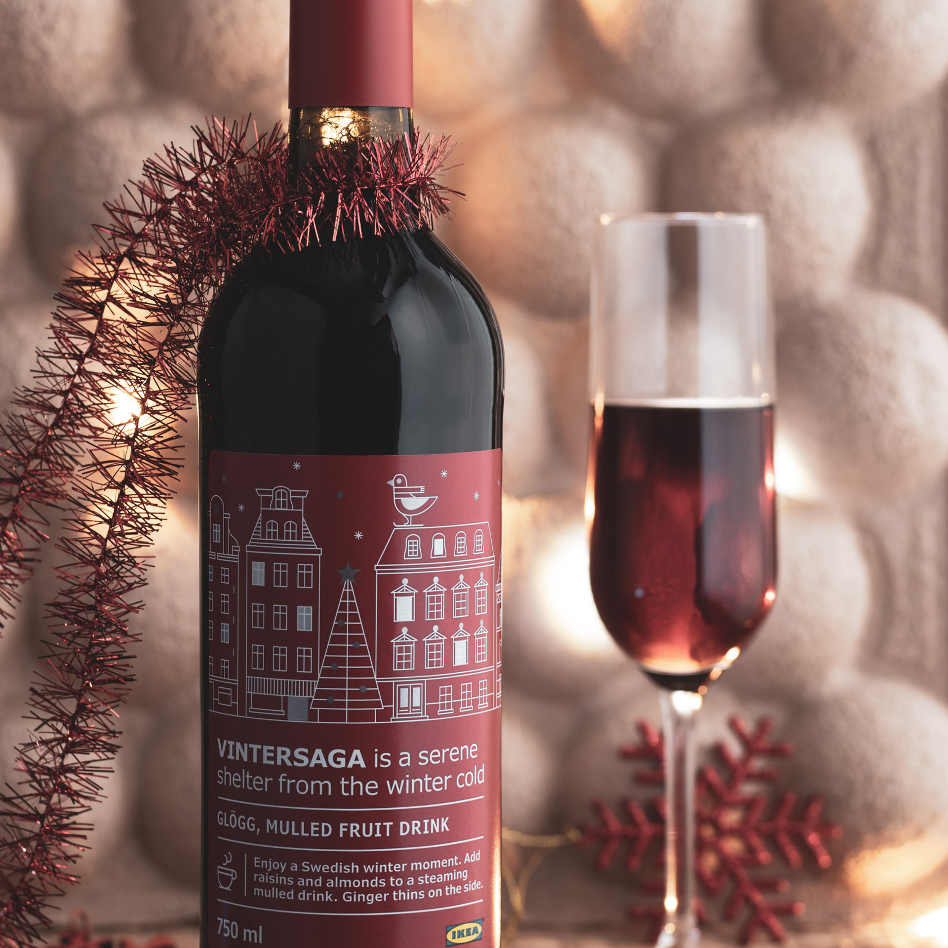 Новогодняя фотография напитка со вкусом глинтвейна. Производства Икея. Напиток в бутылке красного цвета и высоком бокале.
